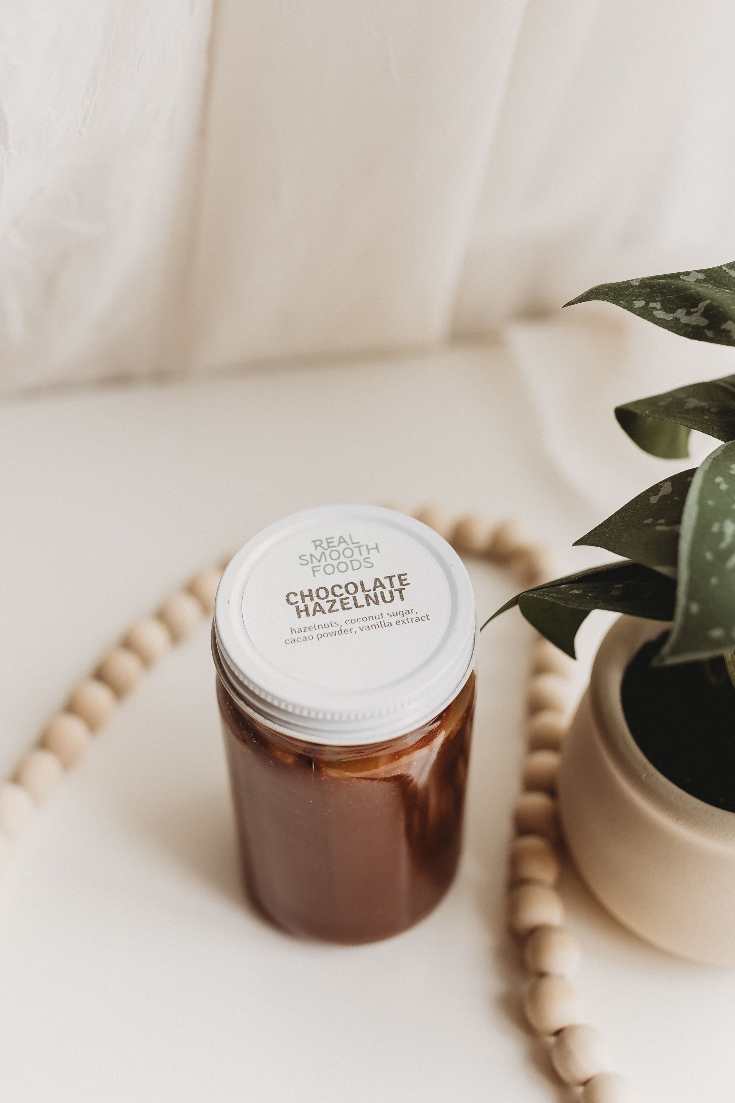  a jar of handmade chocolate hazelnut spread sits on a white backdrop during food product photography 