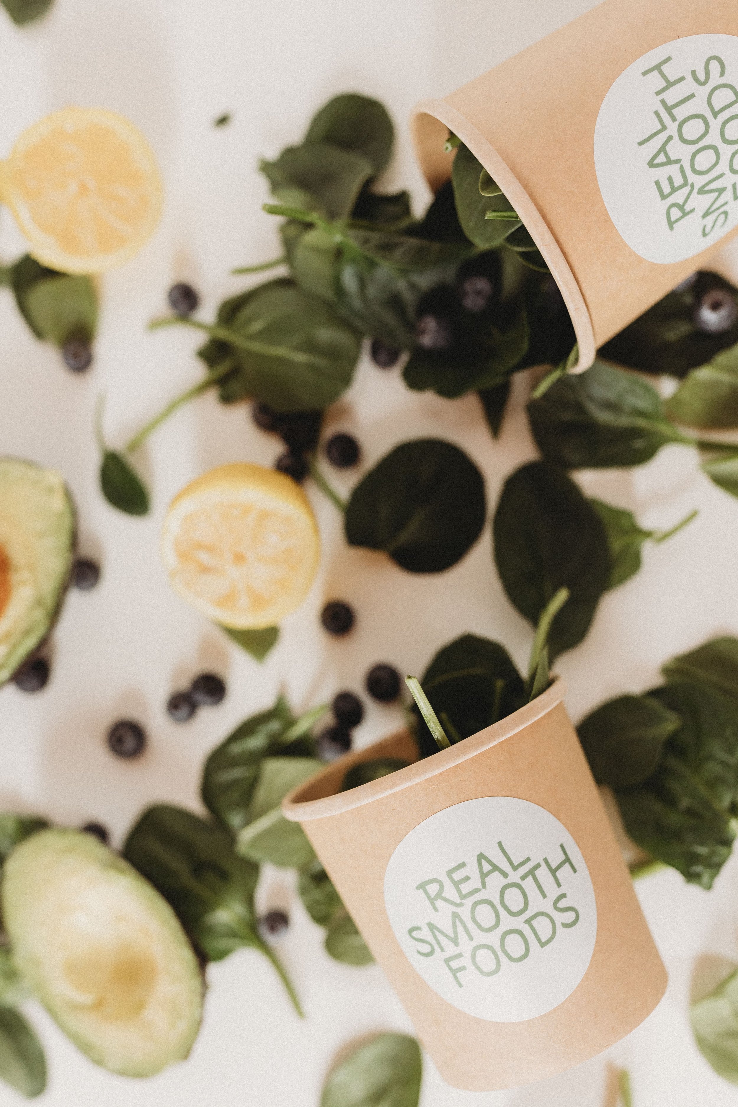  real smooth foods cups with spinach, lemons, and avocado spilling out 