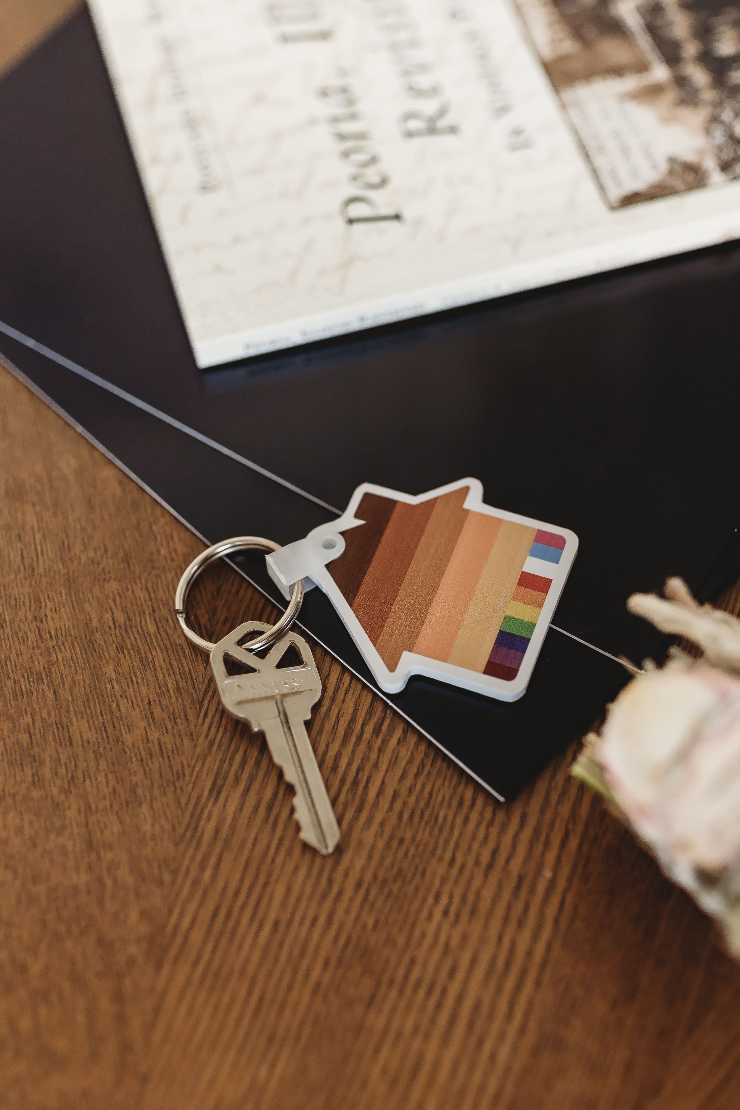  a photo of a set of keys and a house keychain striped with shades of brown and lgbtq+ flags from a realtor brand photo shoot 