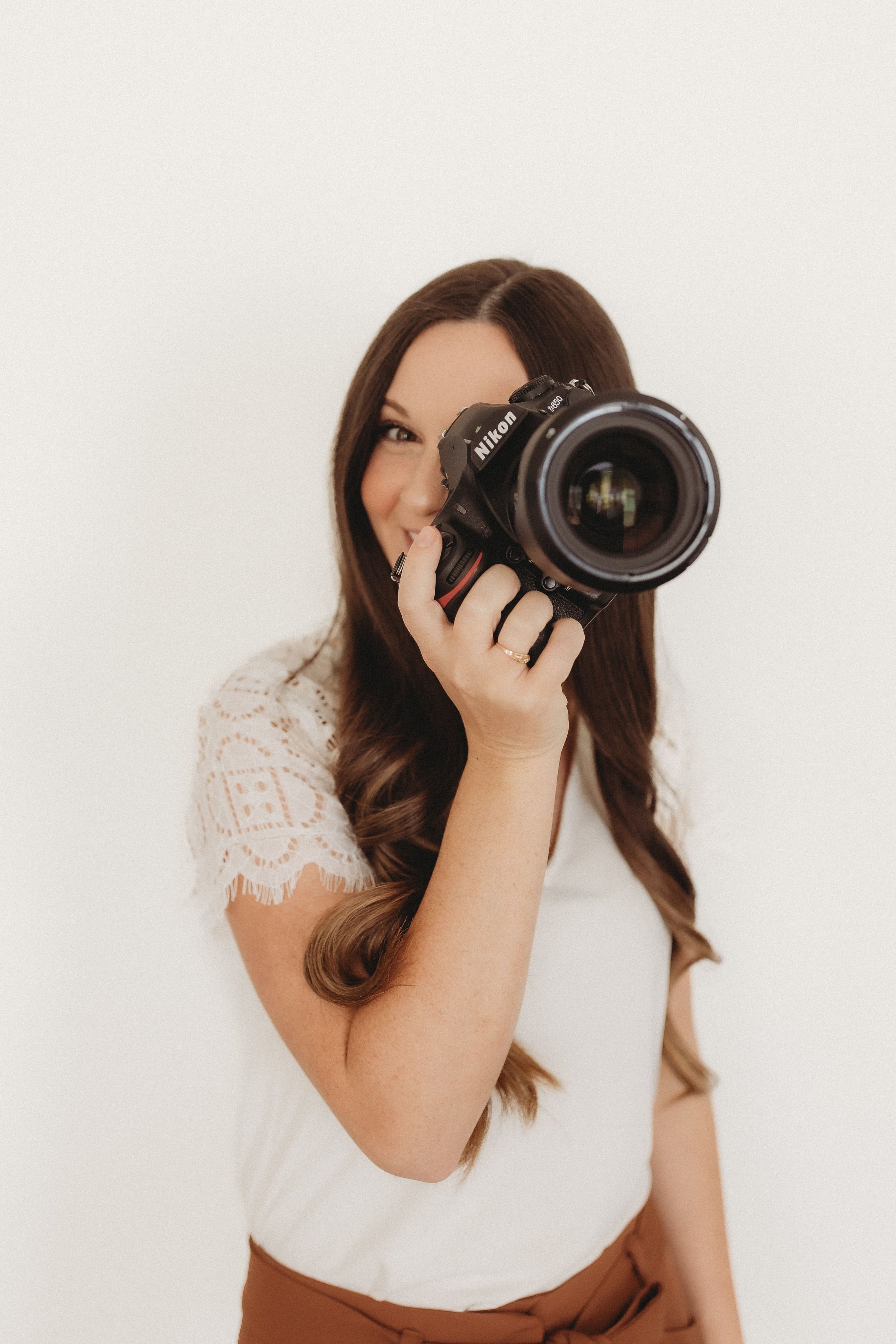  a woman smiles from behind the lens of a professional camera  
