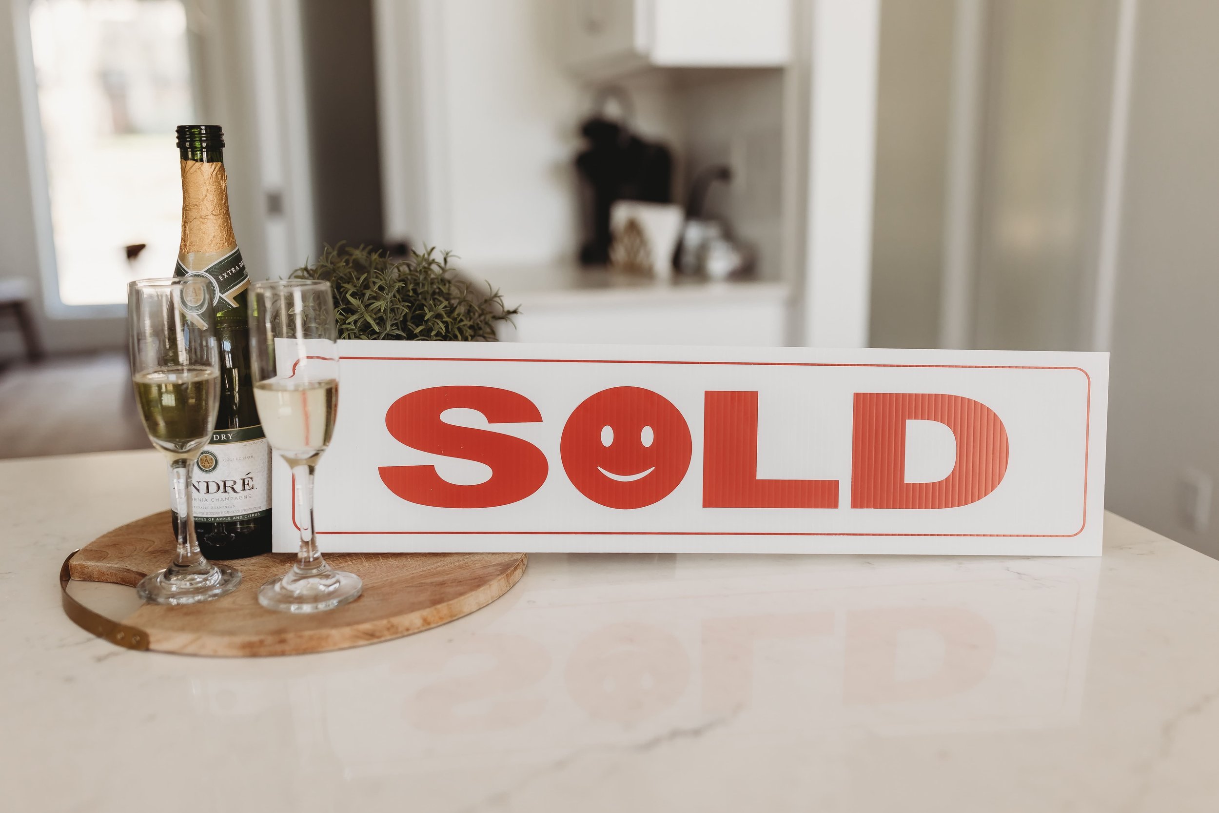  a sold sign sits next to a bottle of champagne and two glasses  
