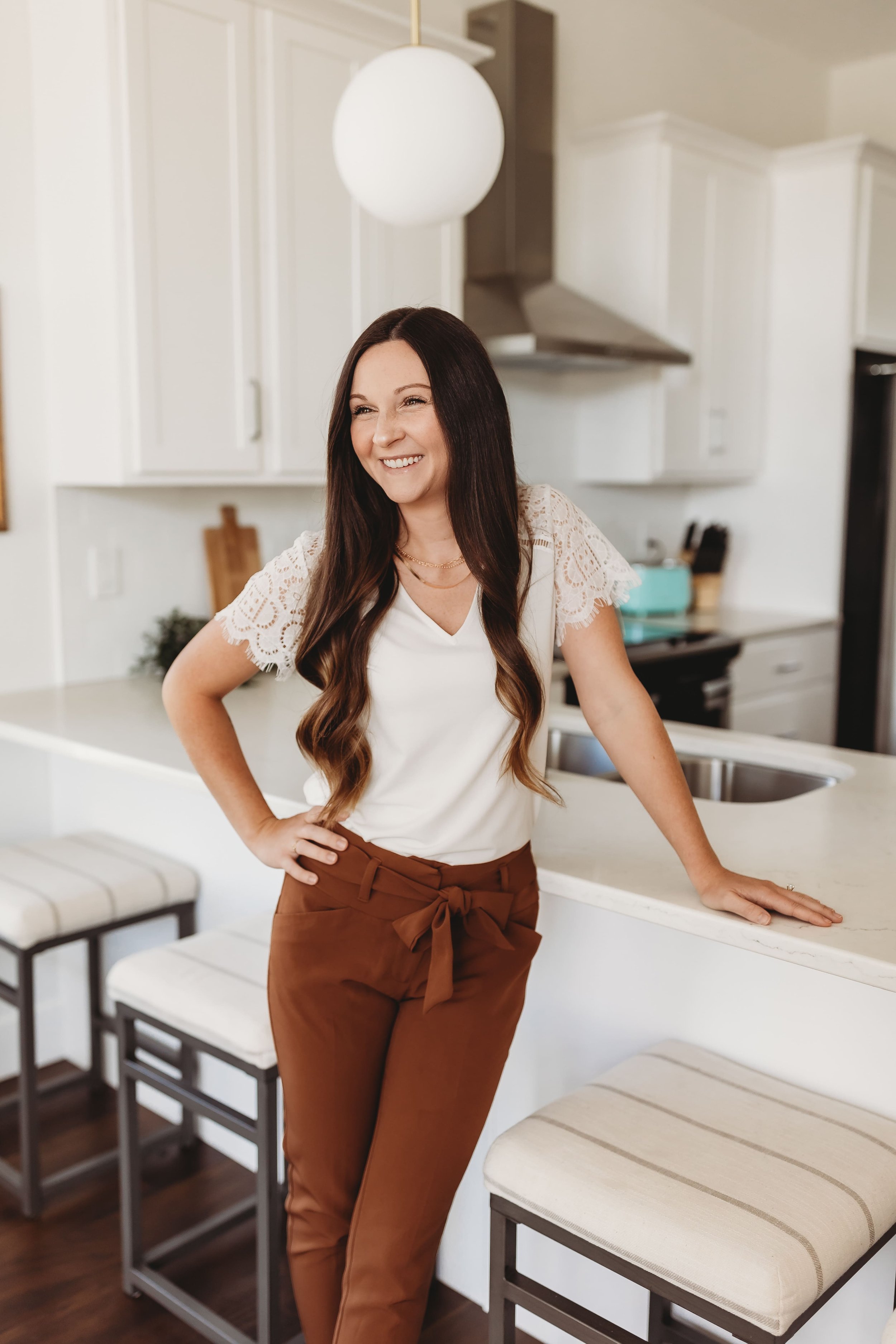  a woman leans against a countertop in a bright kitchen during realtor headshots 