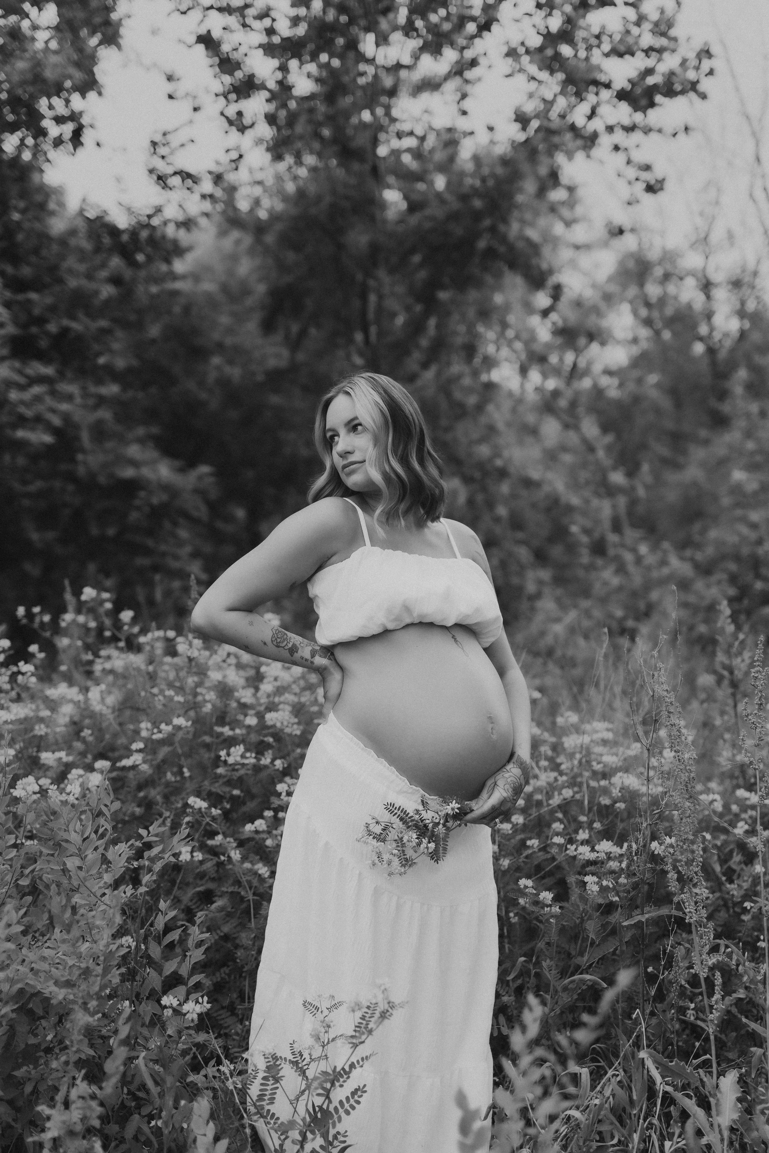  an expectant mother stands in a wildflower field for a maternity photoshoot 