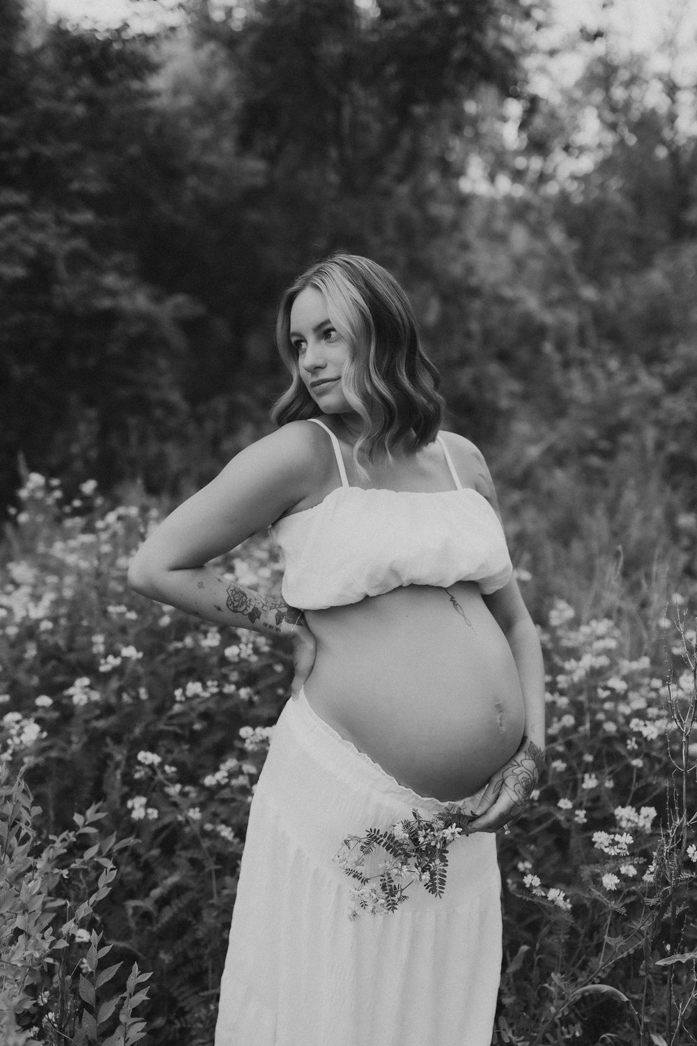  an expecting mother stands in a wildflower field during a shoot with an Illinois maternity photographer 