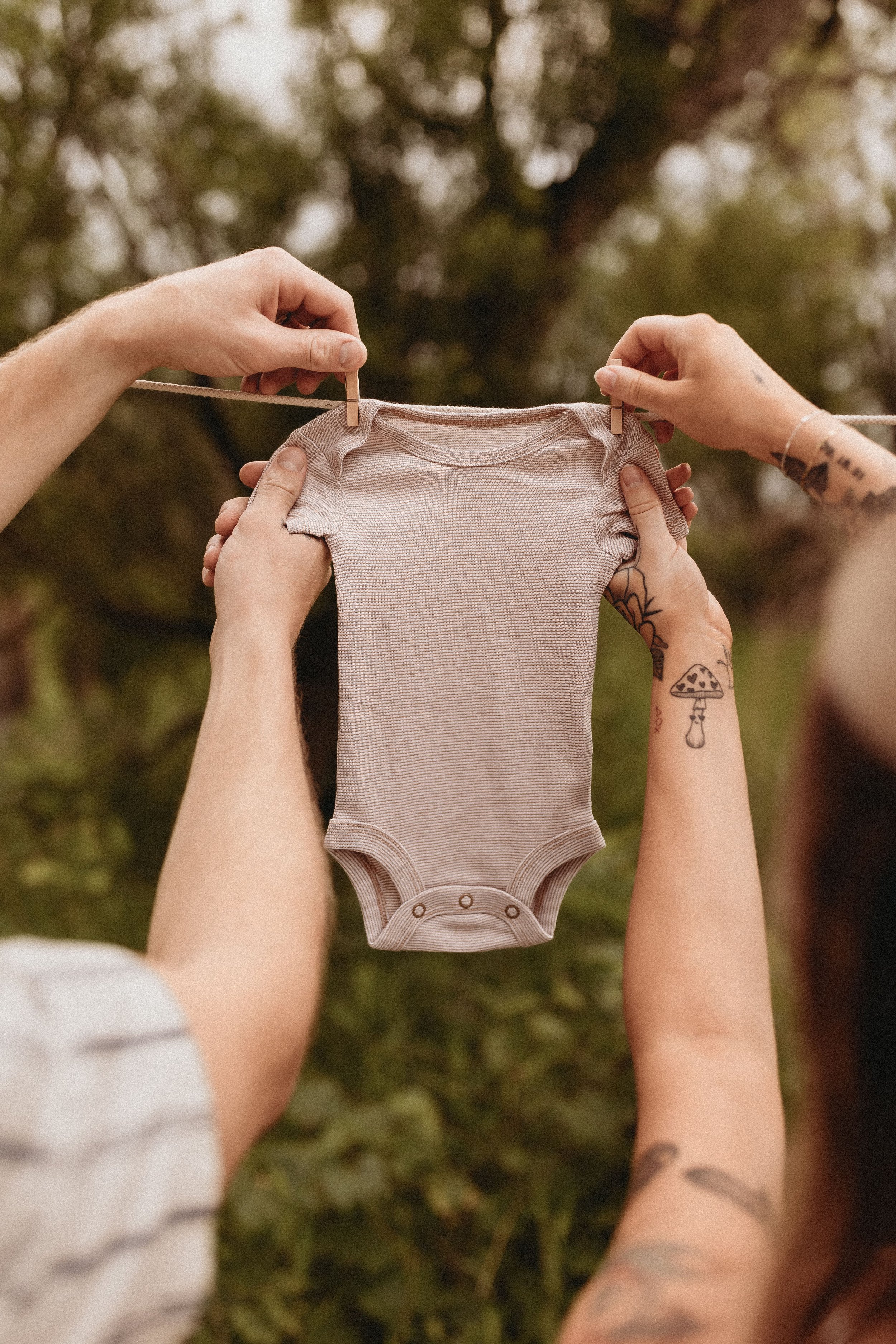  an expecting couple clip a baby onesie on a clothing line during a maternity photoshoot  