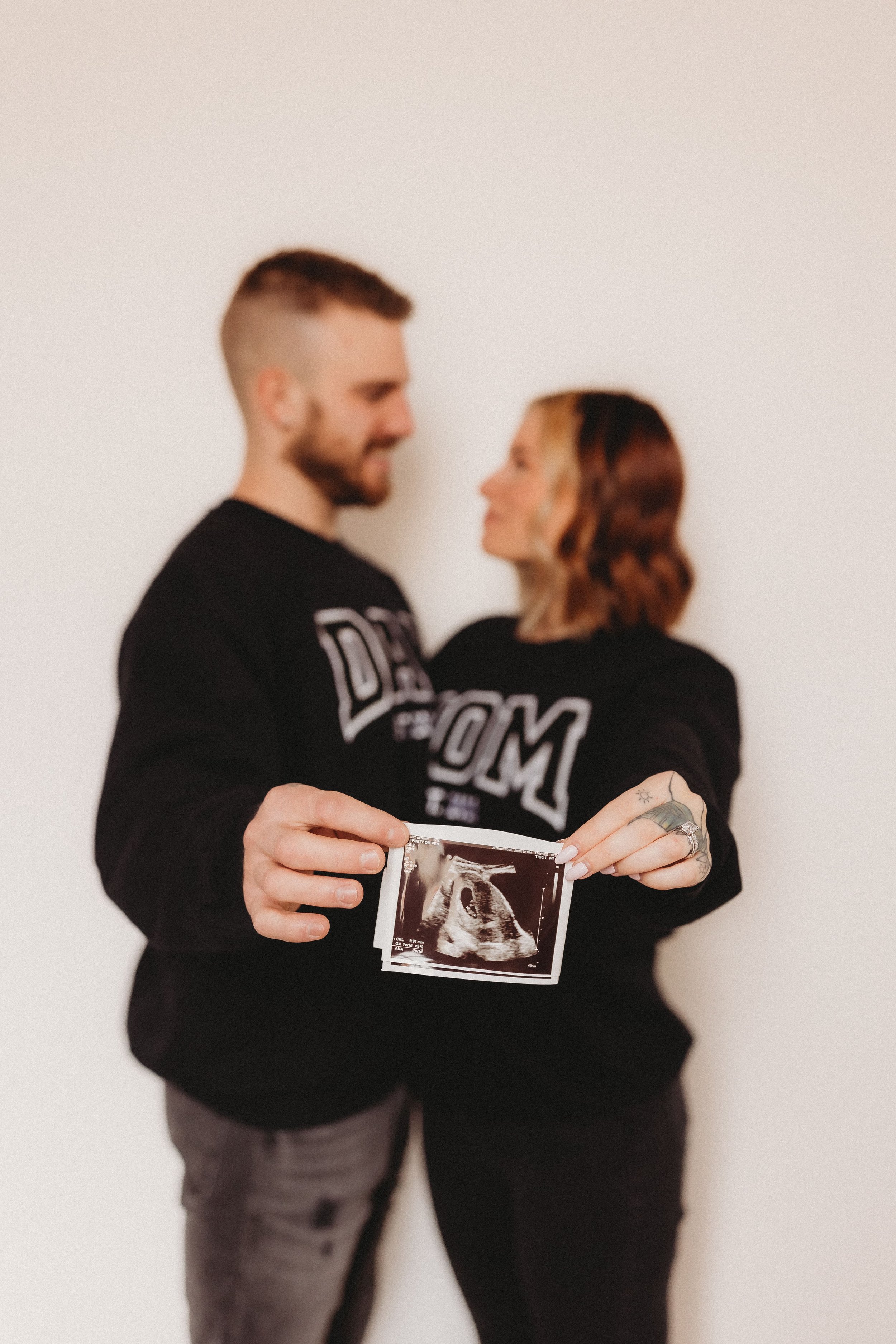  an expecting couple gaze at each other while holding out a sonogram photo 