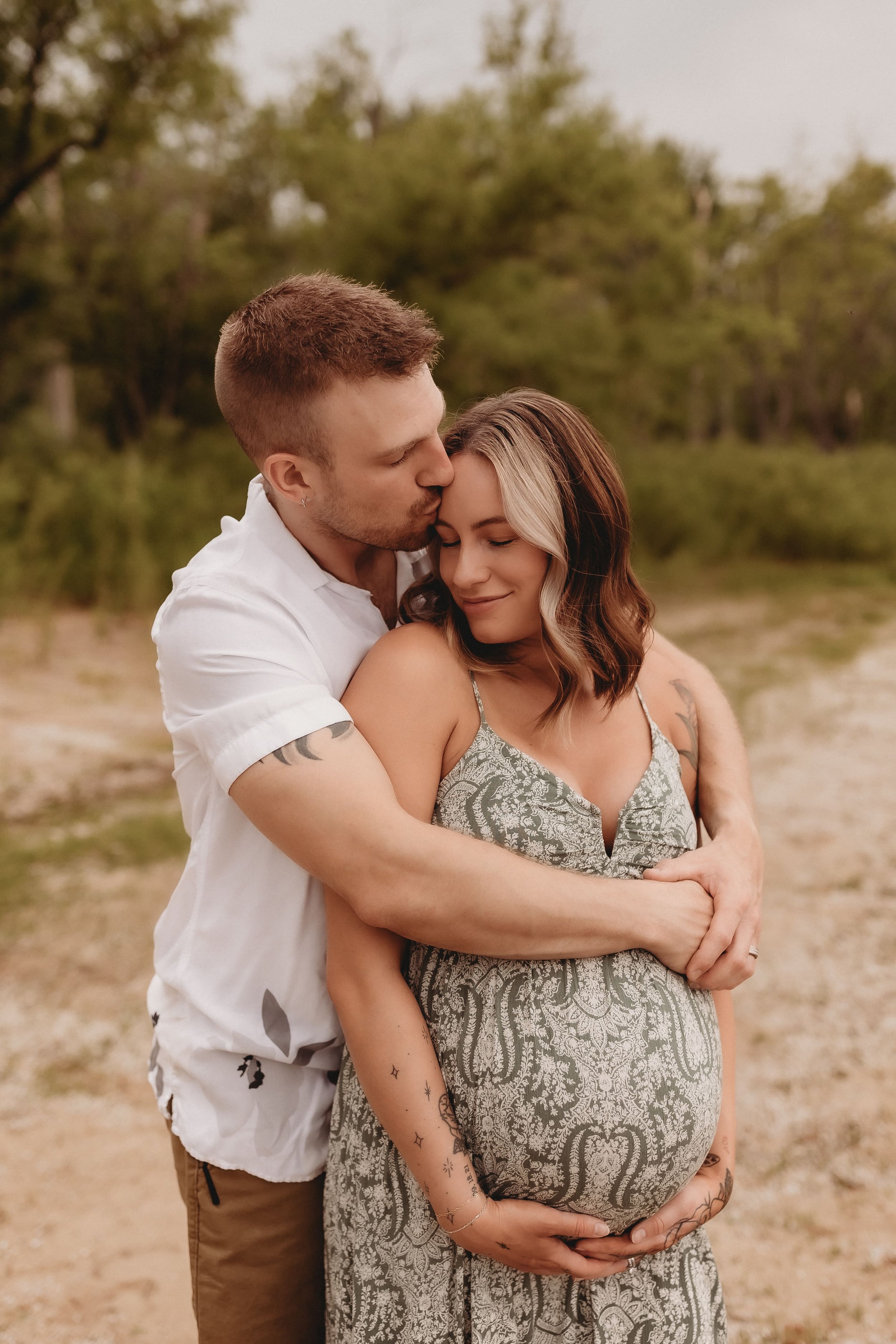  a dad-to-be presses a kiss to his pregnant wife’s forehead during a maternity shoot photographer session 