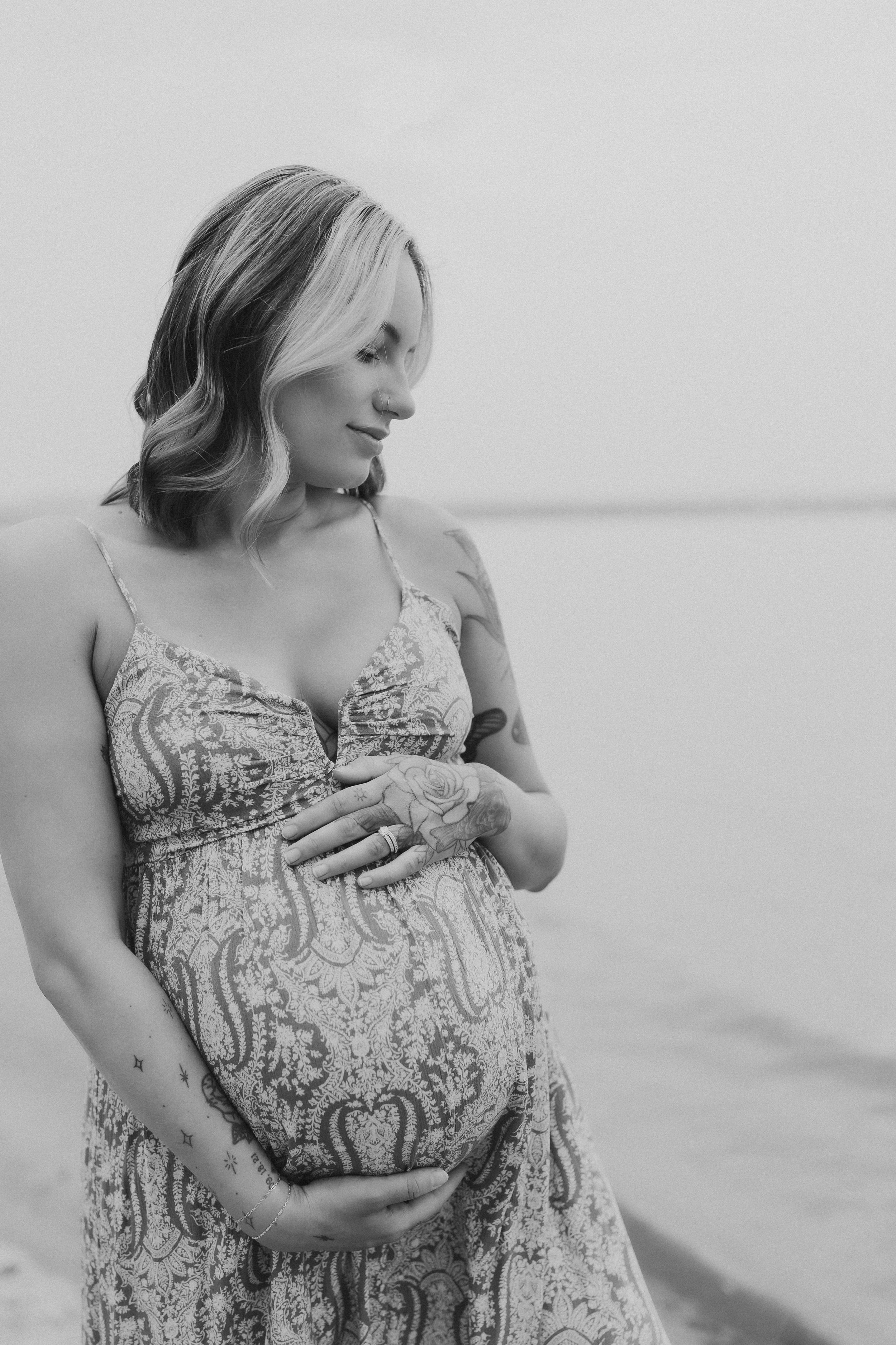  a pregnant woman looks down in front of her maternity shoot photographer 