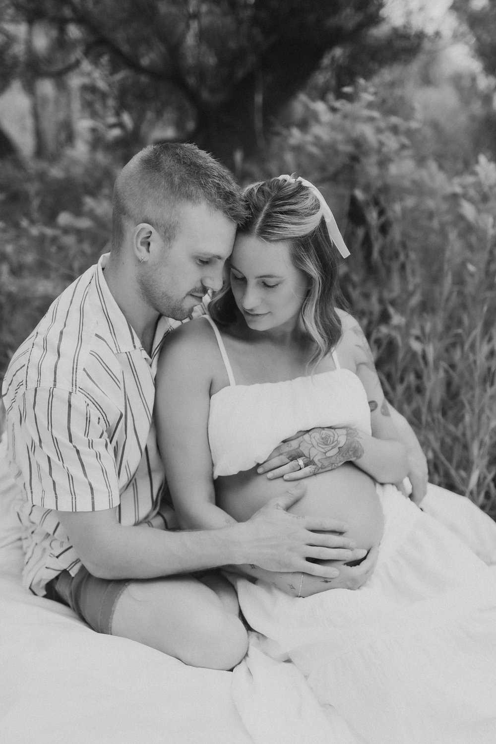  a black and white photo of a mom and dad-to-be nestled together during a session with a maternity shoot photographer 