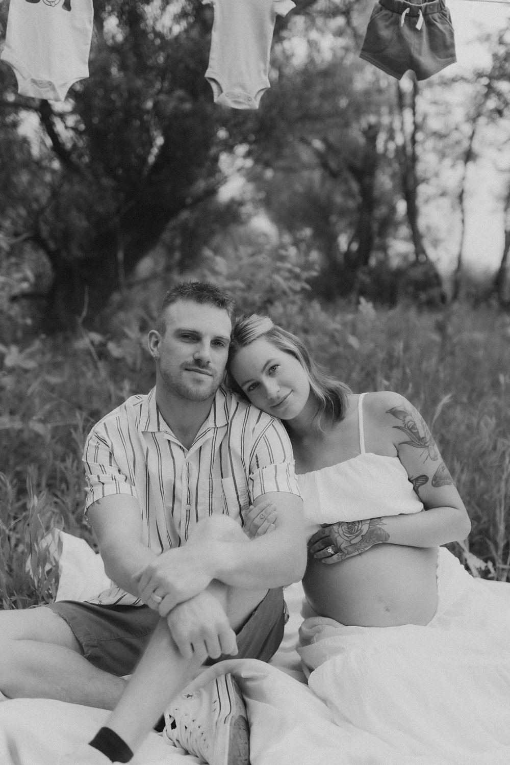  a maternity shoot photographer captures a sweet portrait of an expectant couple on a blanket in a field  