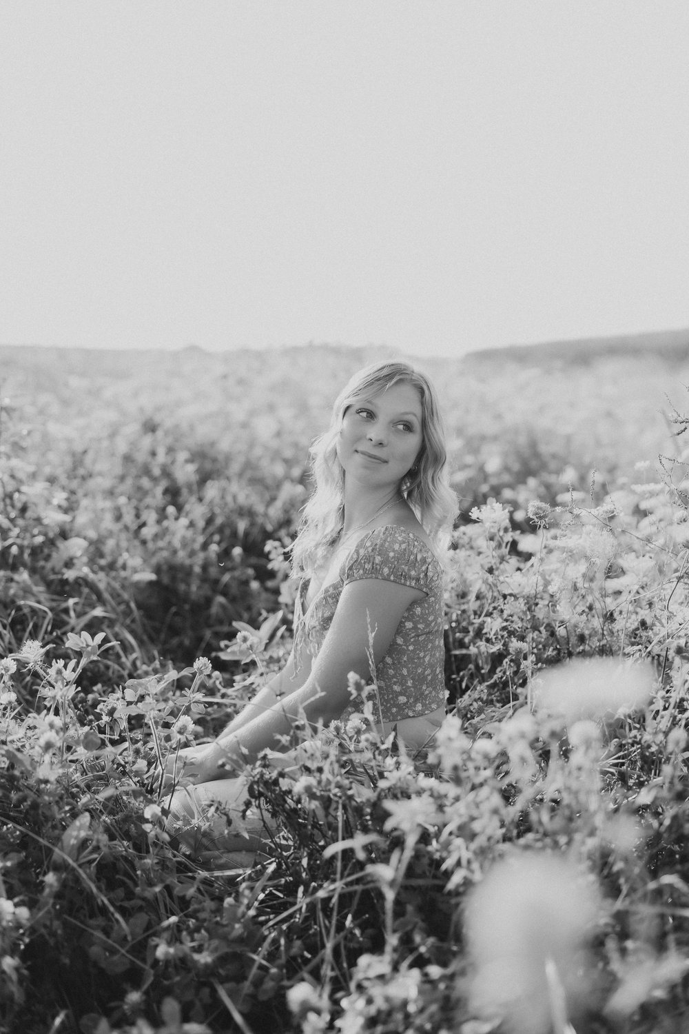  a high school senior looks over her shoulder during portraits in a wildflower field 