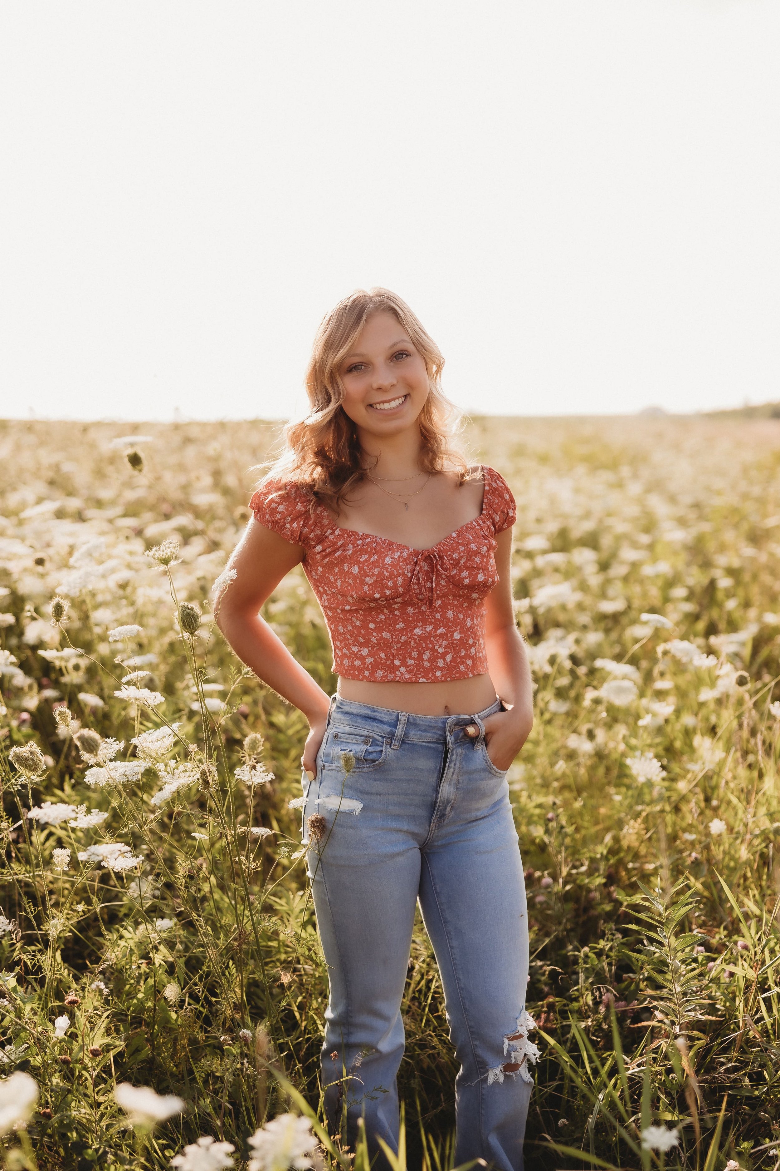  a high school senior smiles for portraits in a wildflower field 