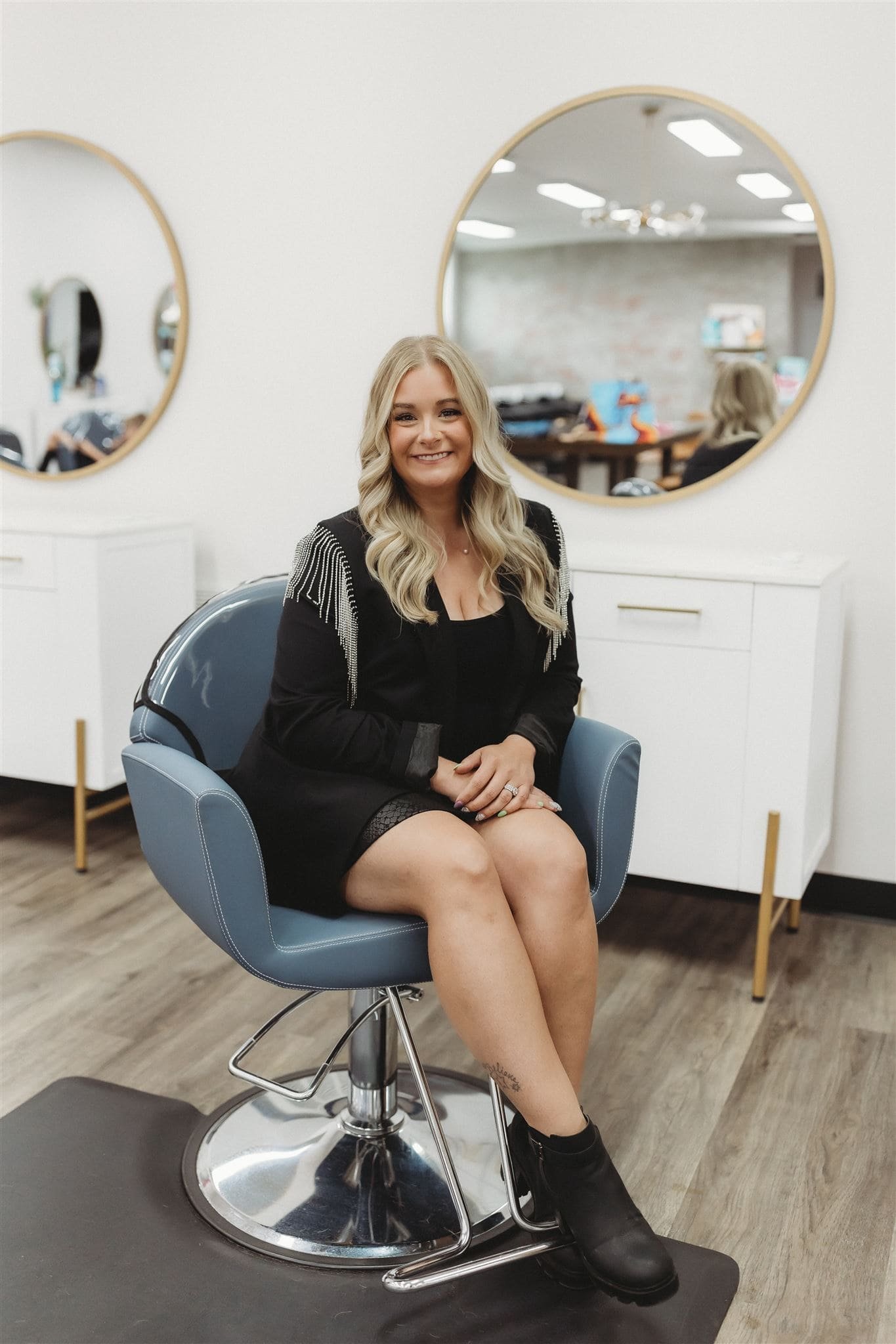  a woman smiles in a hair stylist’s chair for an on-site business headshot 