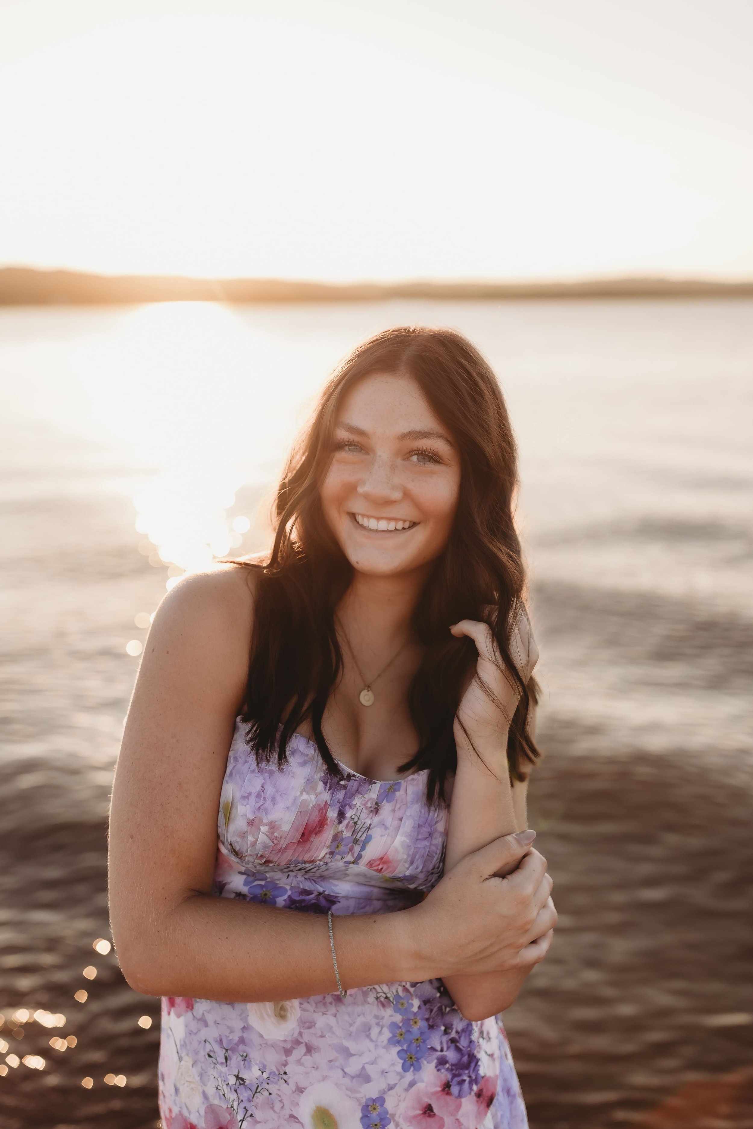  olivia smiles as the sun sets behind her during her senior pictures beach front on the illinois river   