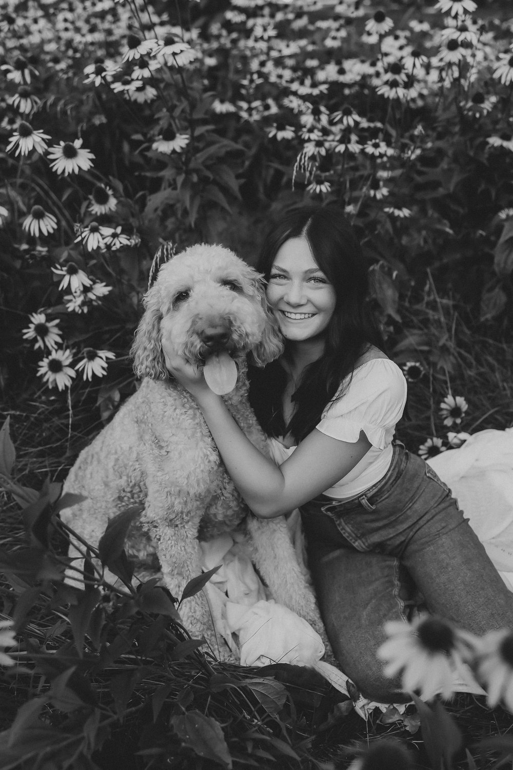  olivia and her dog smile in a grassy flowery area  