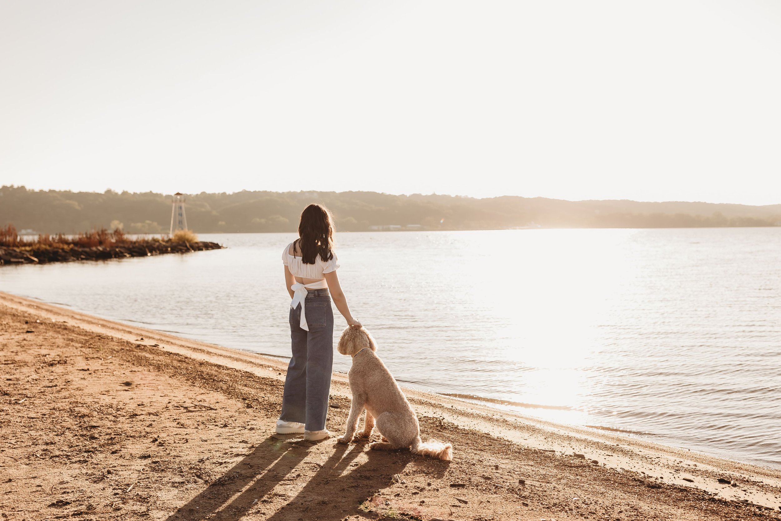  olivia looks out over the water with her pup for her senior pictures beach front in central illinois 