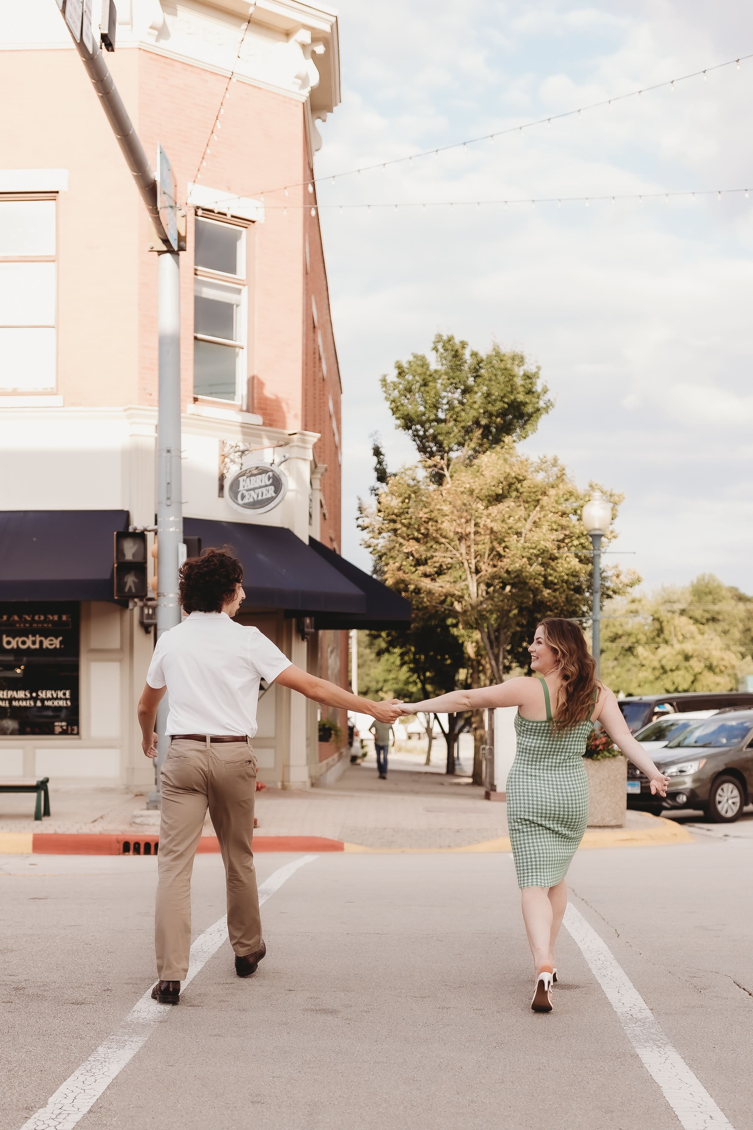  a couple hold hands as they walk across the street during a shoot with a couples photographer 