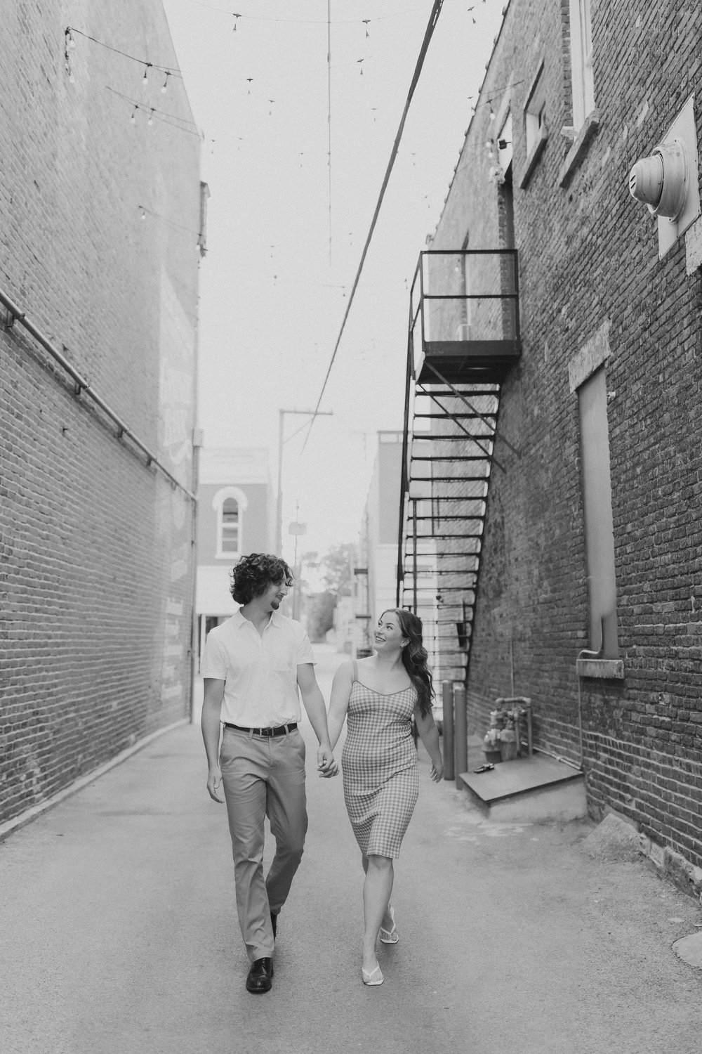 a couple walk together down an alley while holding hands 