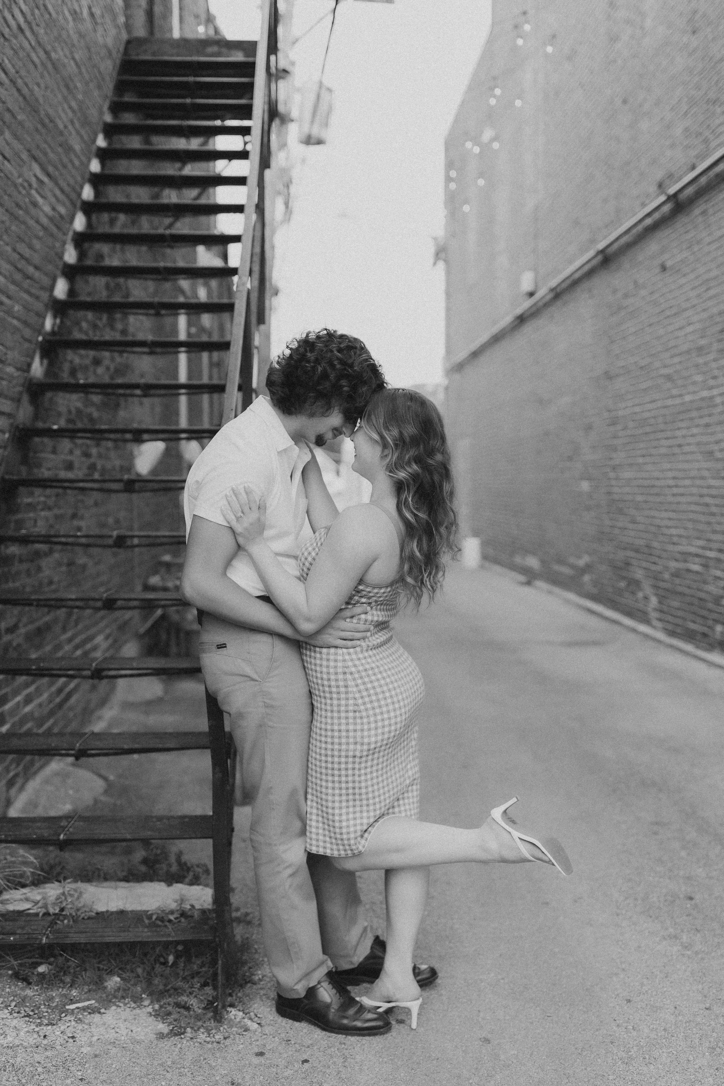  a couple lean together against a fire escape during a session with an engagement photographer 