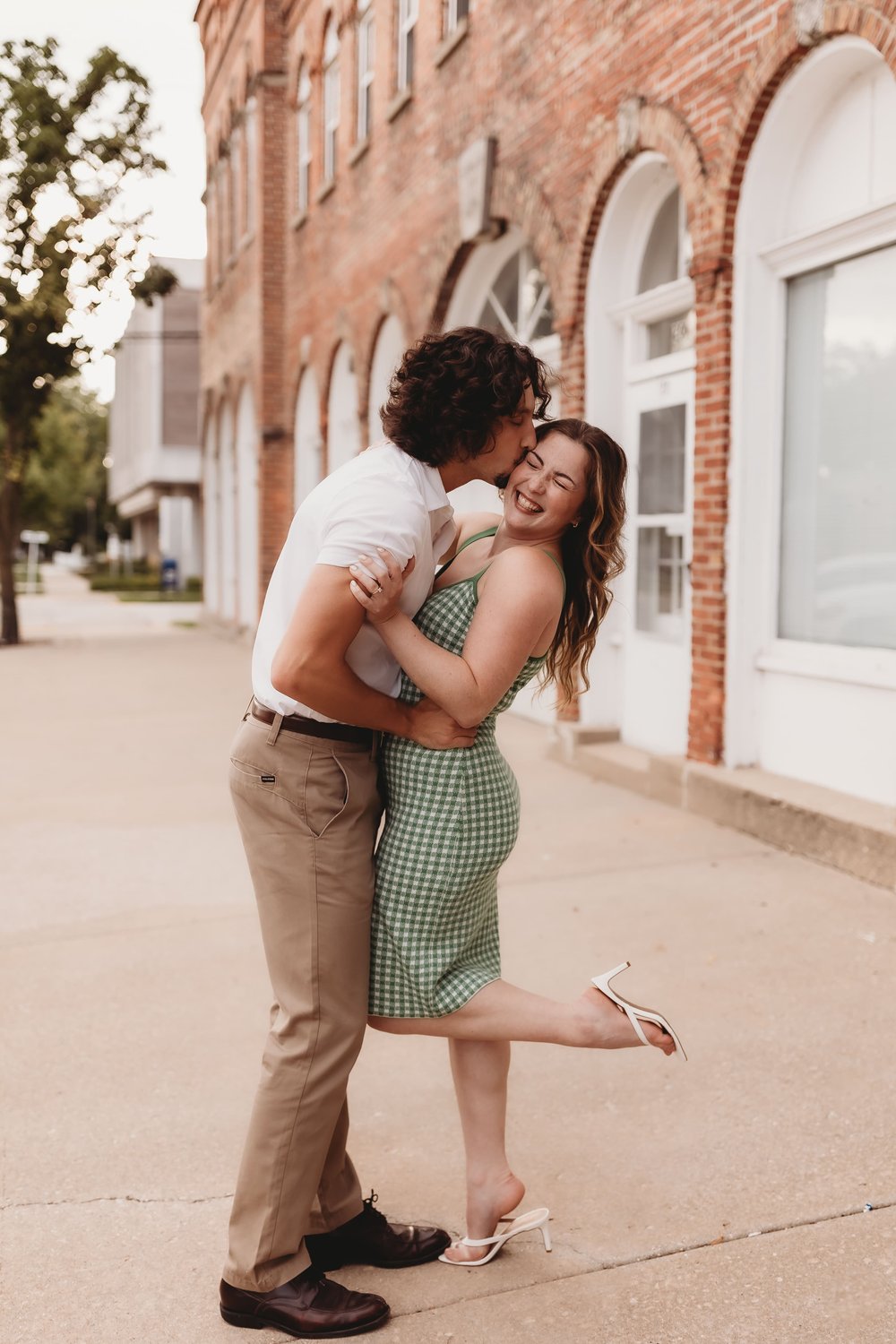  a man kisses the side of his fiancee’s face during their engagement photos 