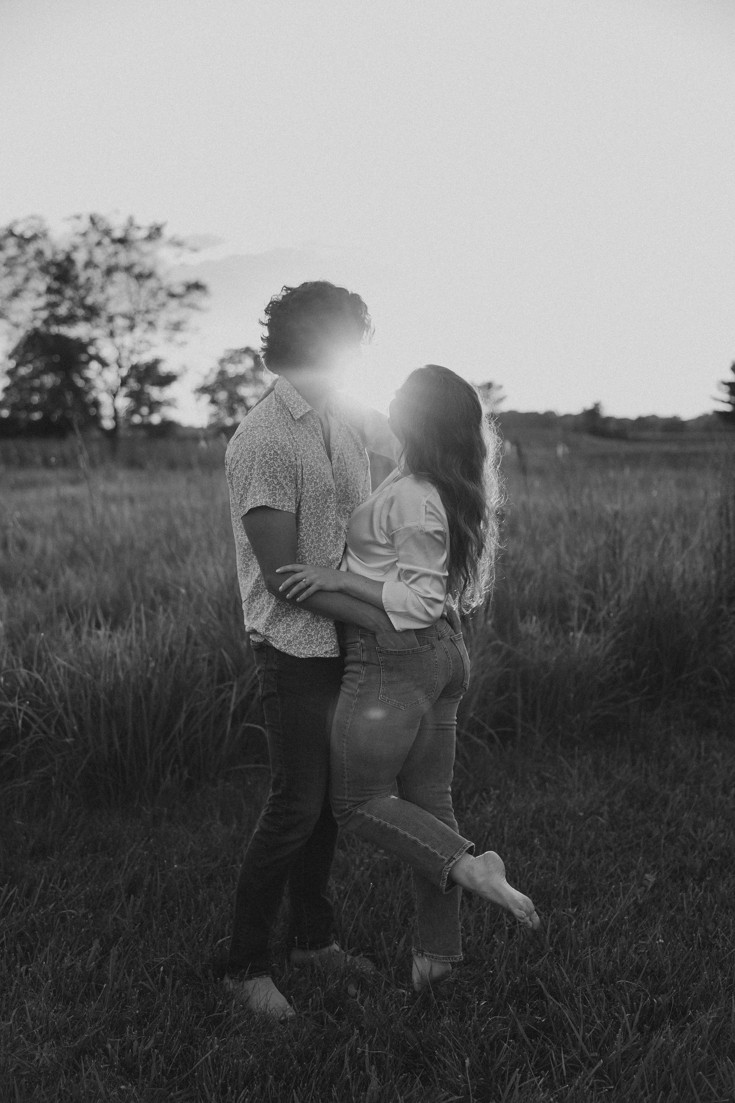  a couple dances in a field as the sun sets 