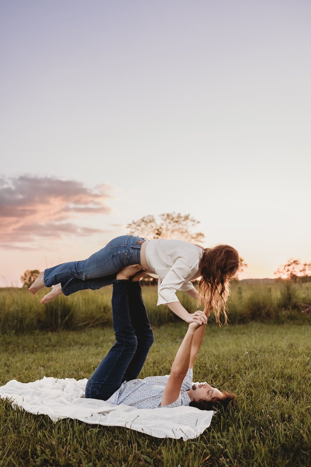  a couple do an airplane on a picnic blanket during blue hour at a session with their engagement photographer 