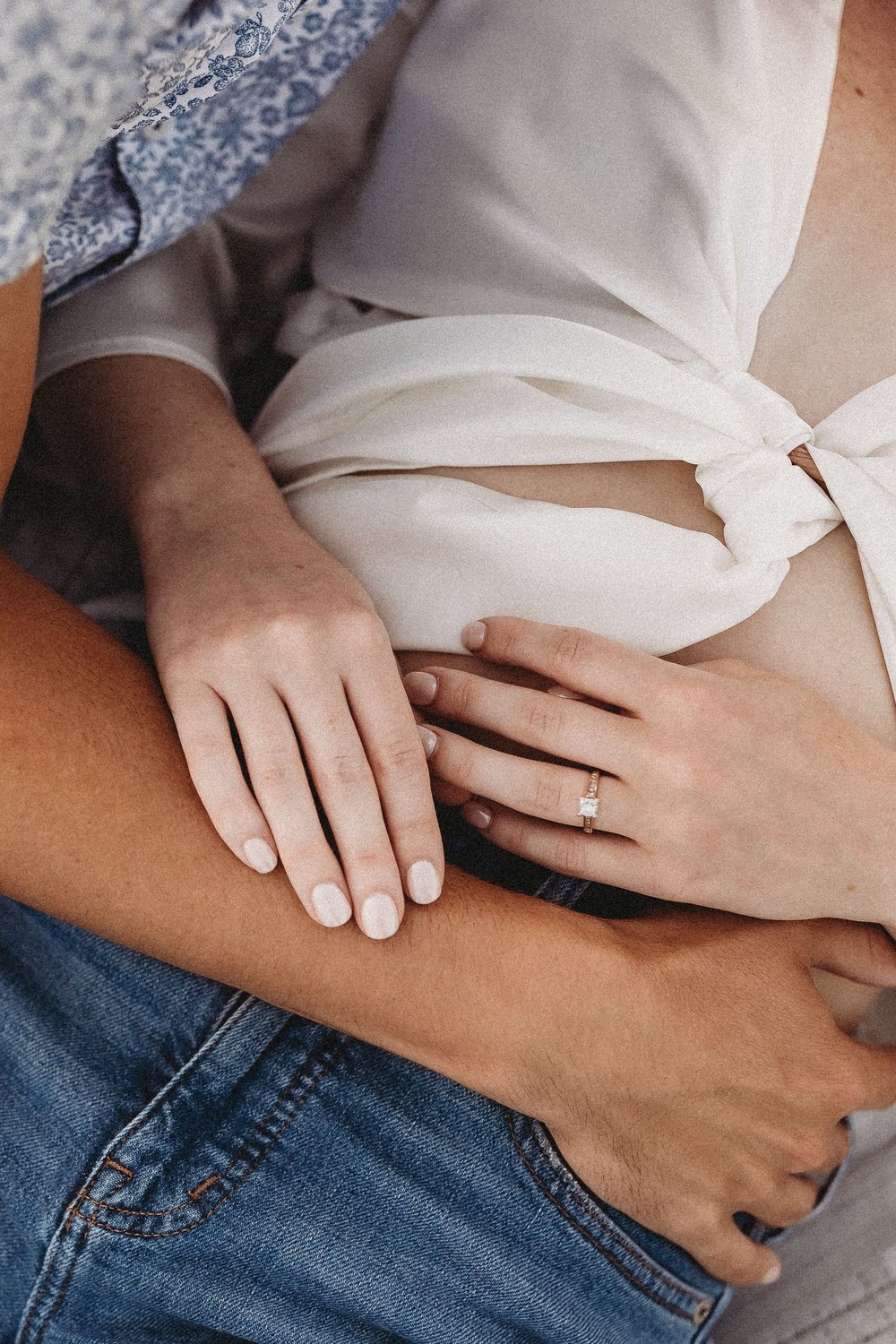  a close up of a couples torsos as they wrap their arms around each other during a session with their engagement photographer 