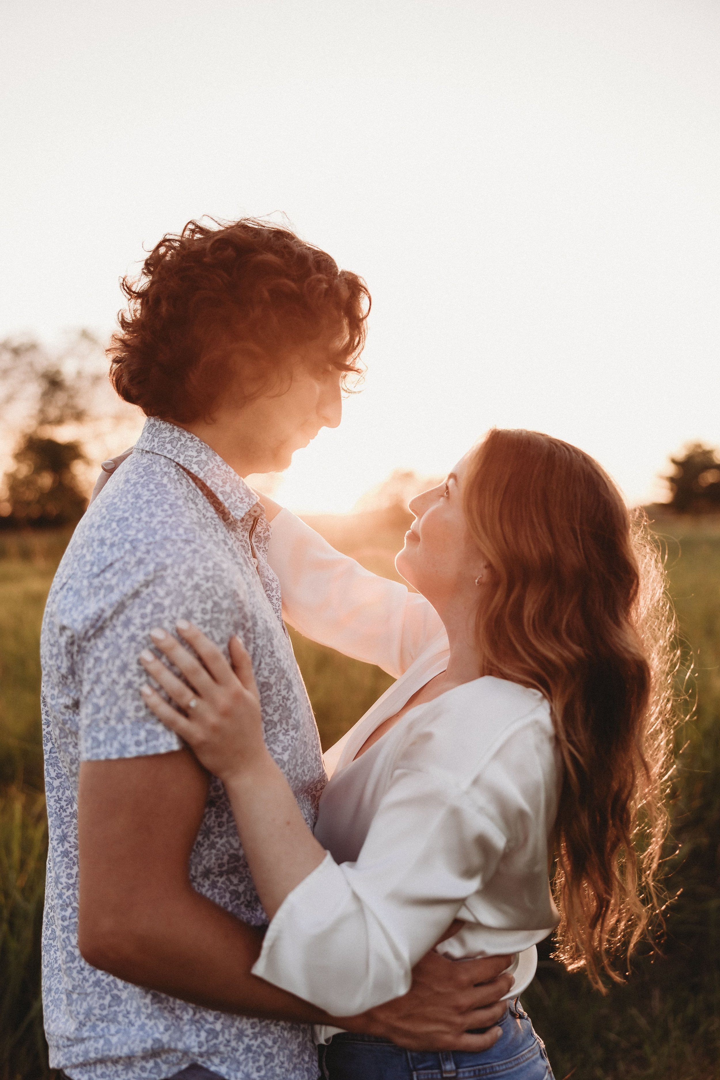  an engaged couple share an embrace as the sun sets behind them,  