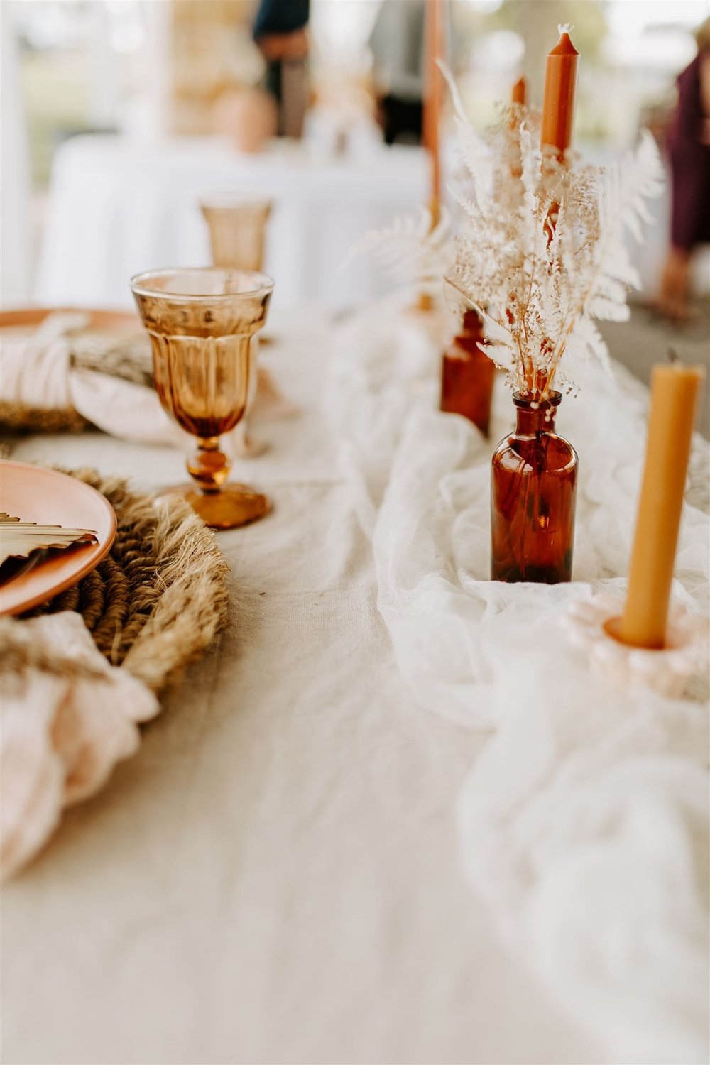  a boho table set up with amber glasses and bottles and dried florals 