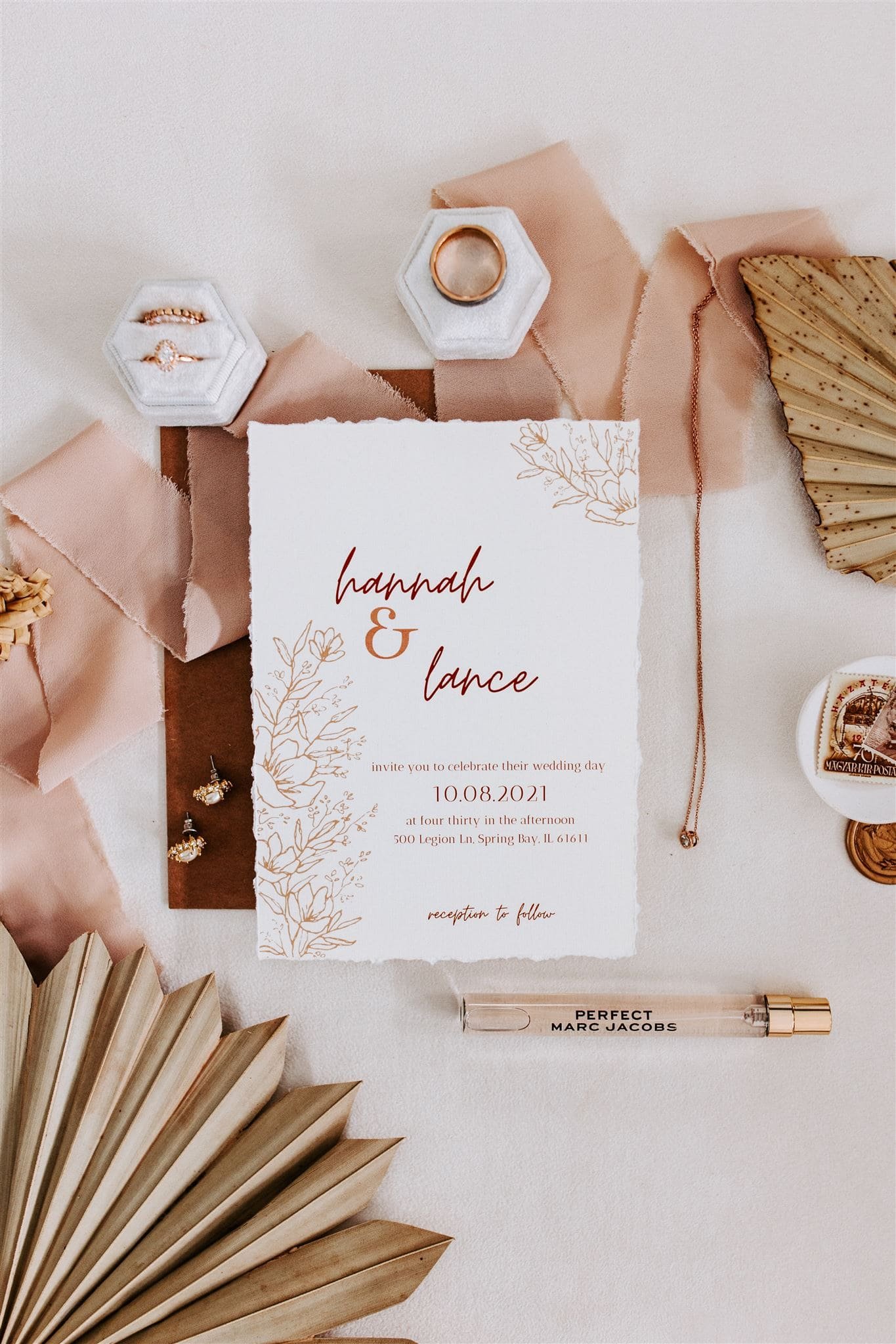  wedding recap, a flatlay of wedding stationary suite, a sample of her purfume, her jewelry, a ribbon and dried florals 