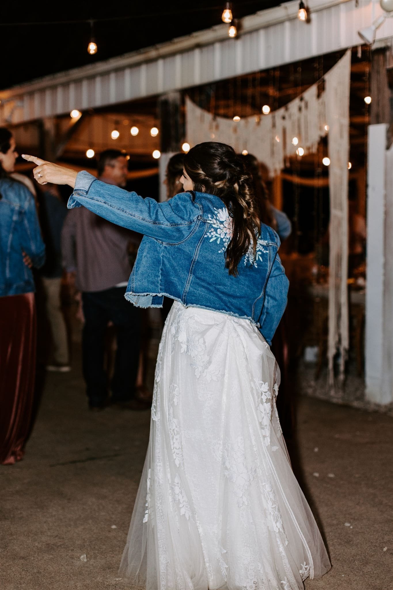  hannah points to something off camera during her wedding reception 