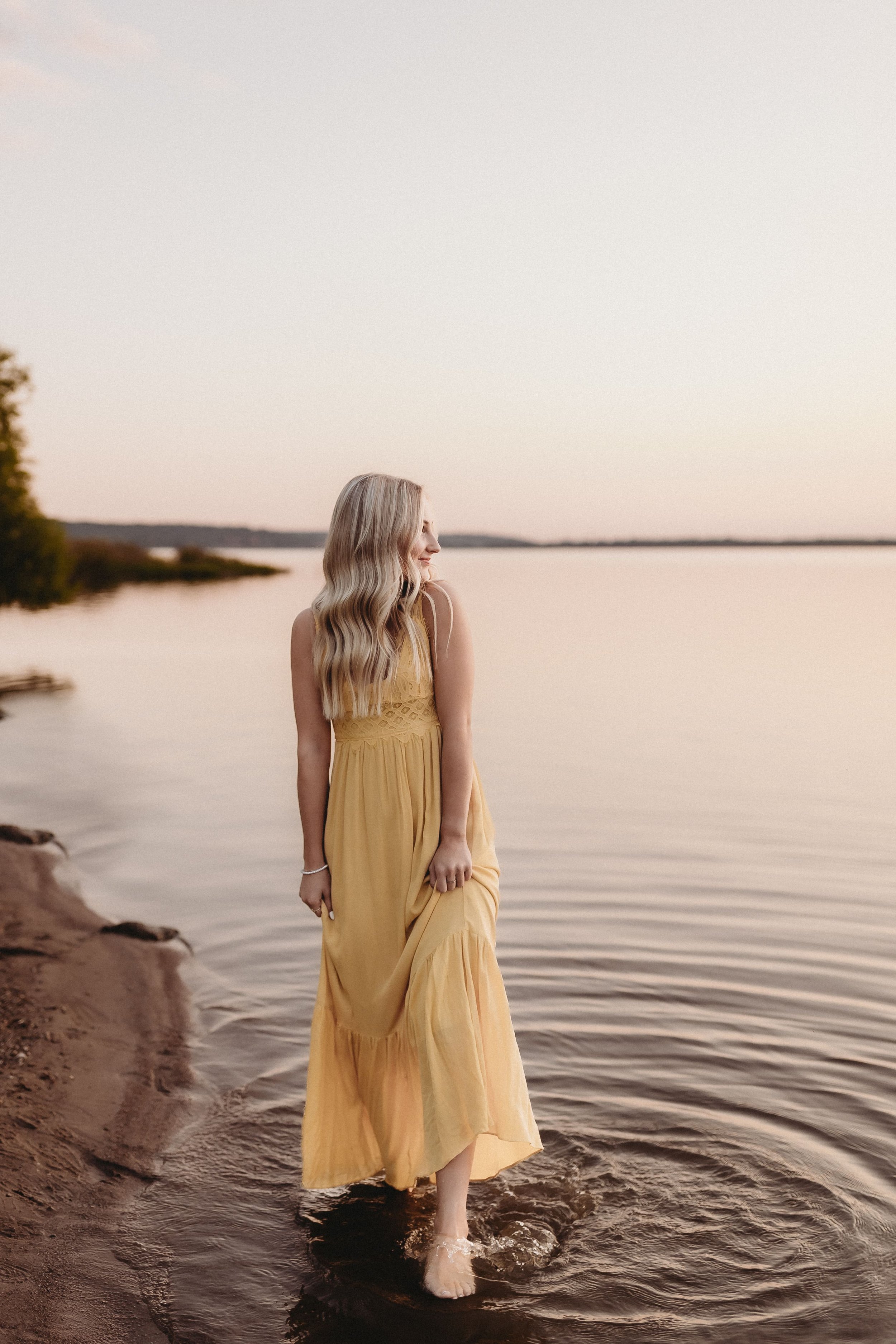  for her senior photo shoot, parker stands barefoot in the illinois river while wearing a long yellow dress 