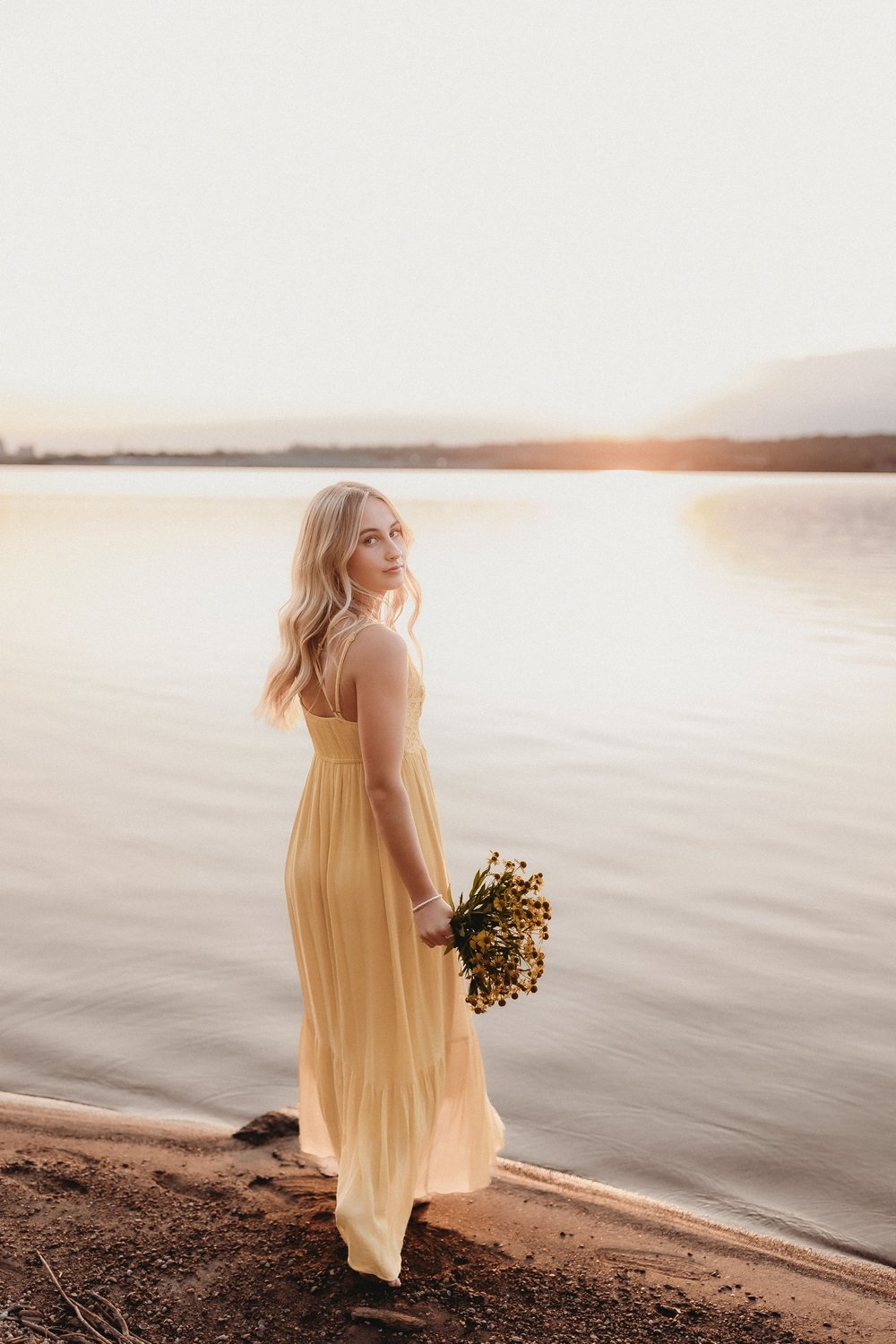  parker looks over her shoulder while wearing a yellow dress on the banks of the illinois river  