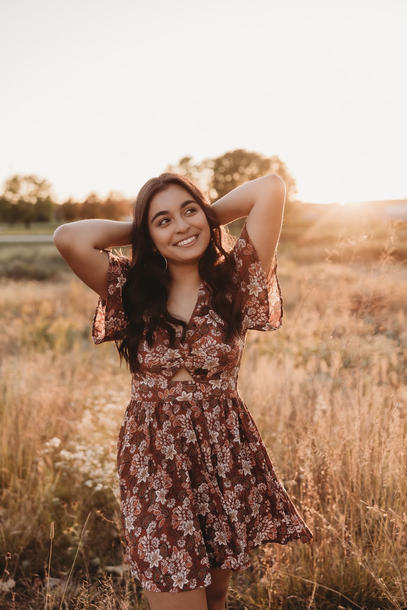  a young woman smiles with her arms behind her head for her senior photography 