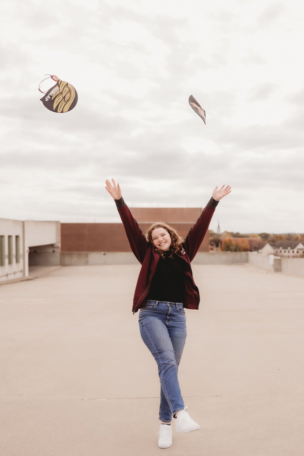  a young girl throws a high school activity accessory in the air while kicking a foot up   