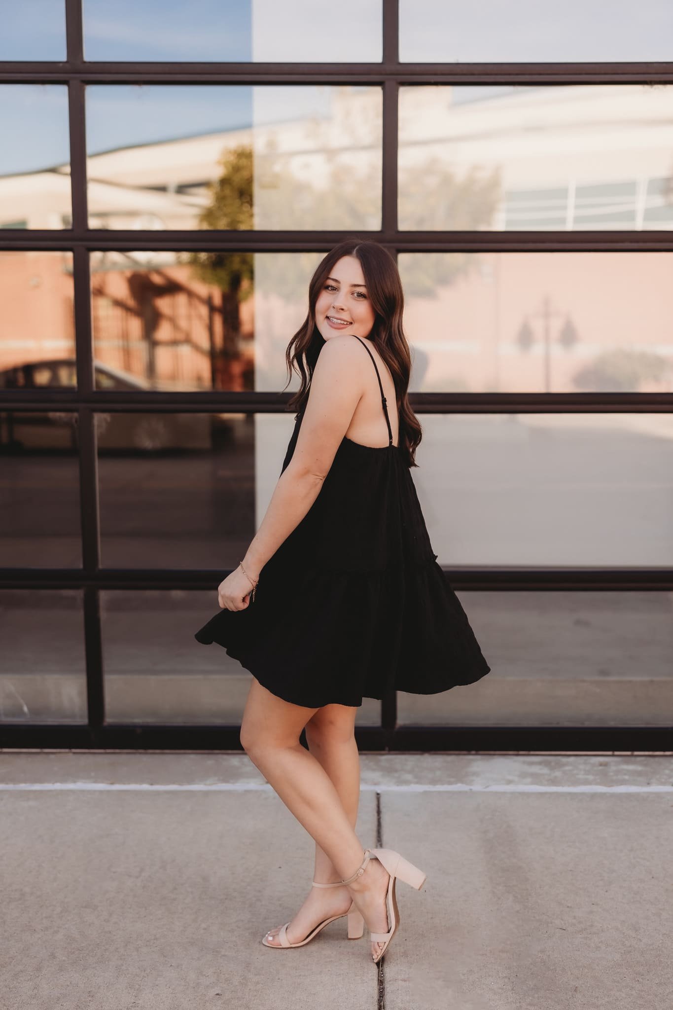  a young woman smiles while spinning in a black dress 