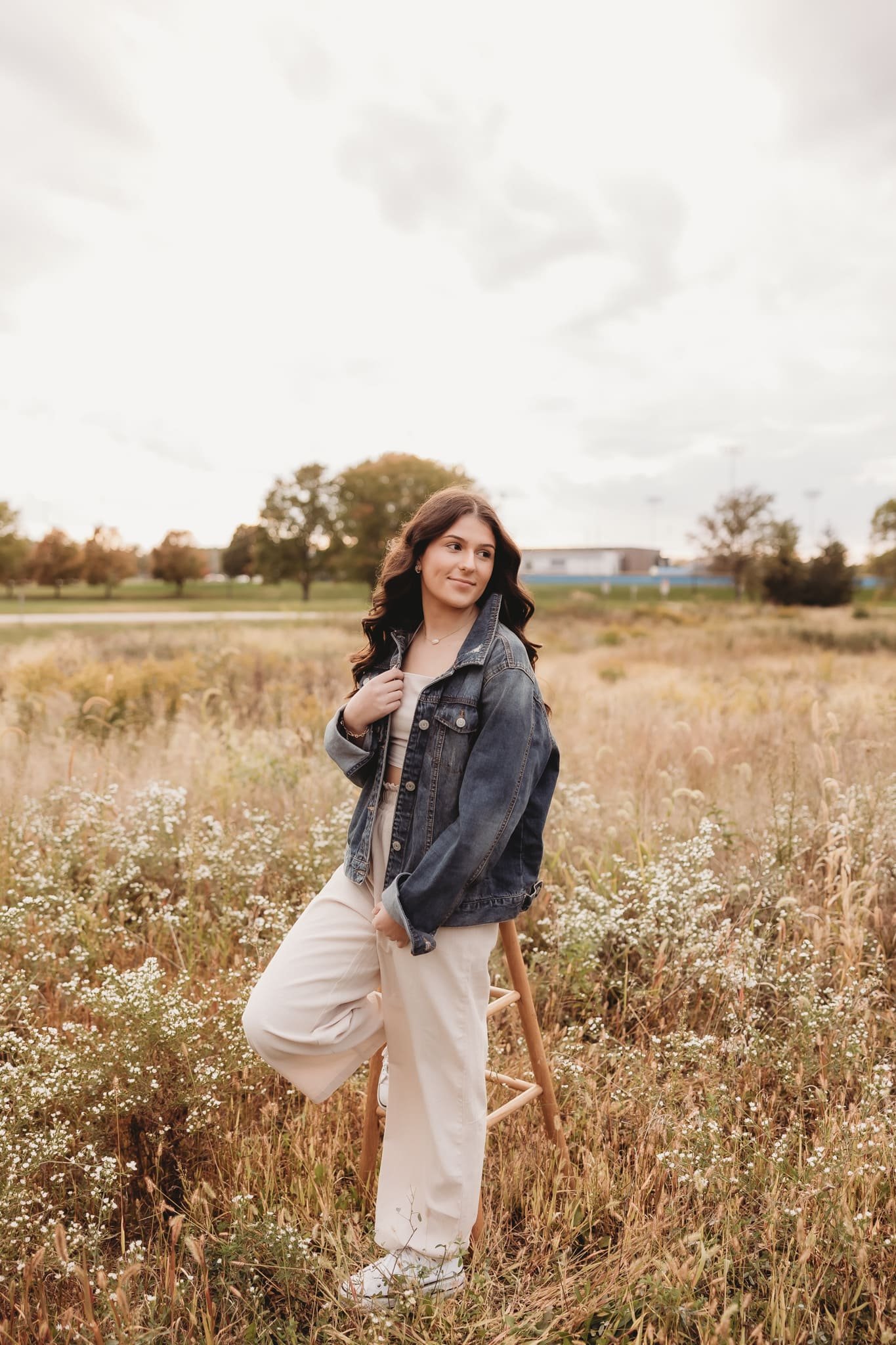  a young woman smiles and looks to the side in an open field 