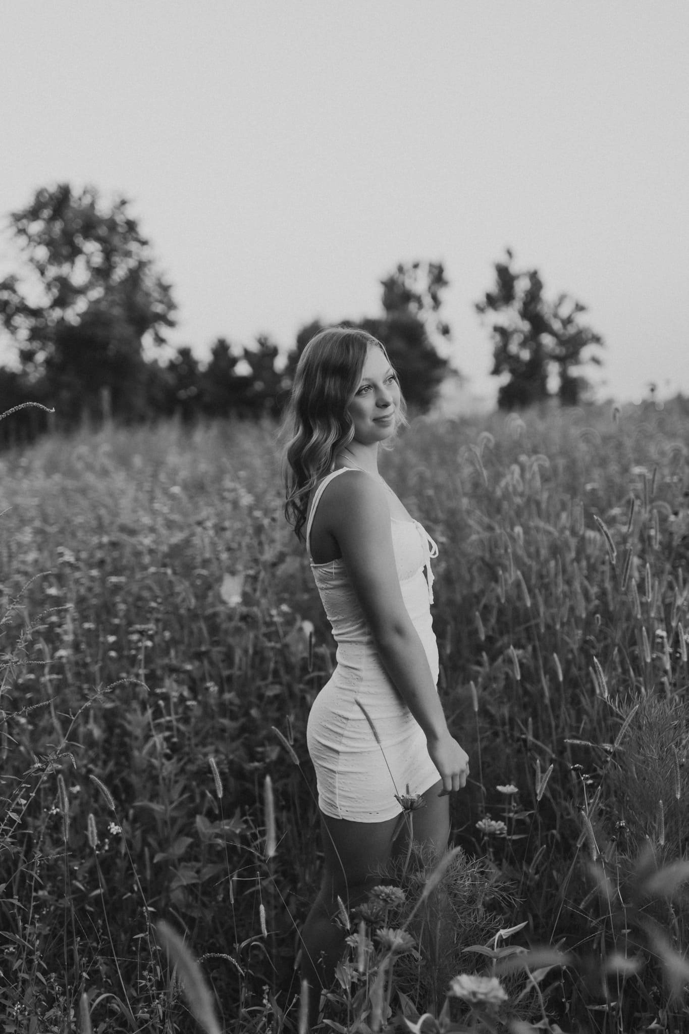  a girl looks out into the distance while standing in a field 