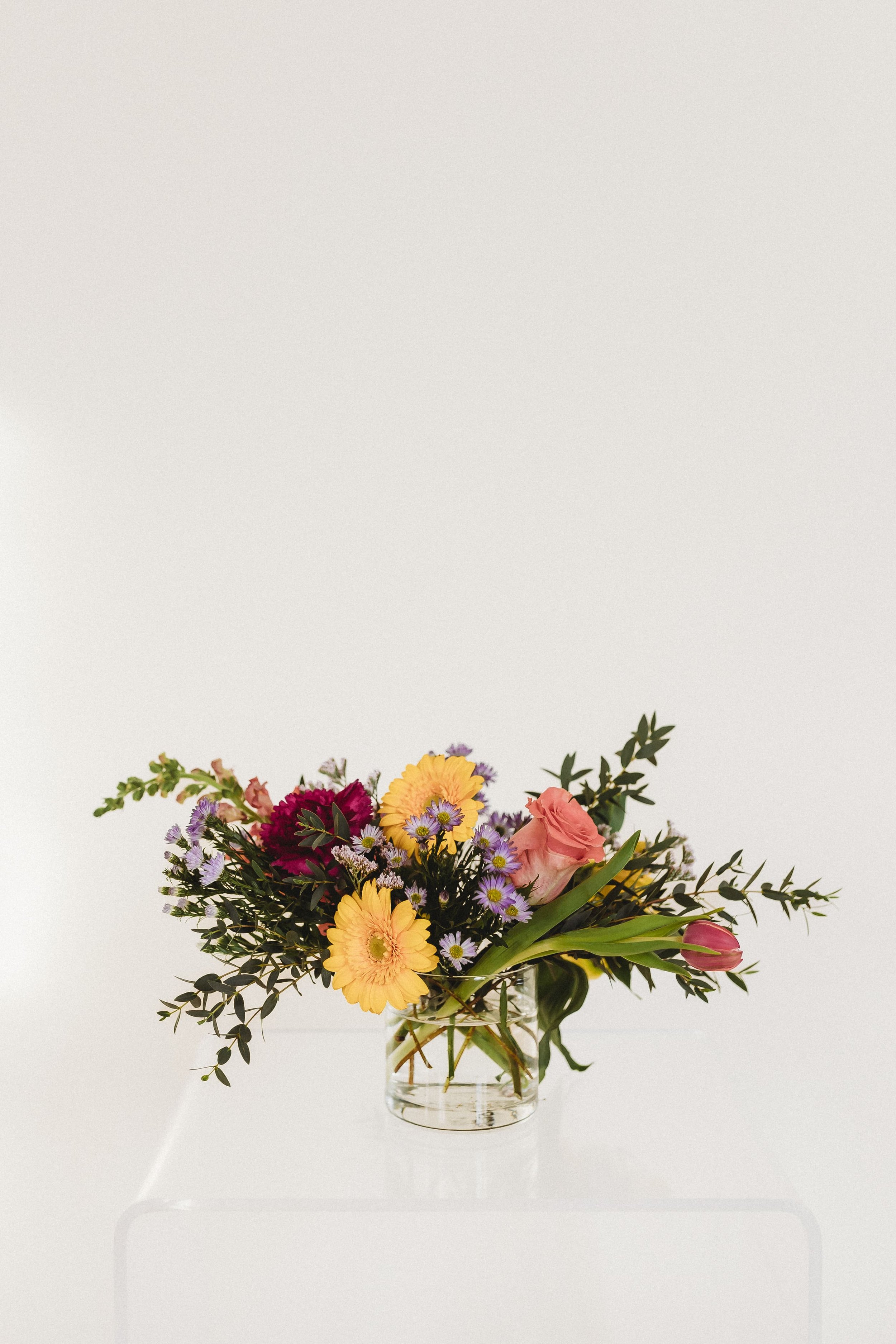  a colorful bouquet of flowers sits on a clear acrylic table for business branding photography 