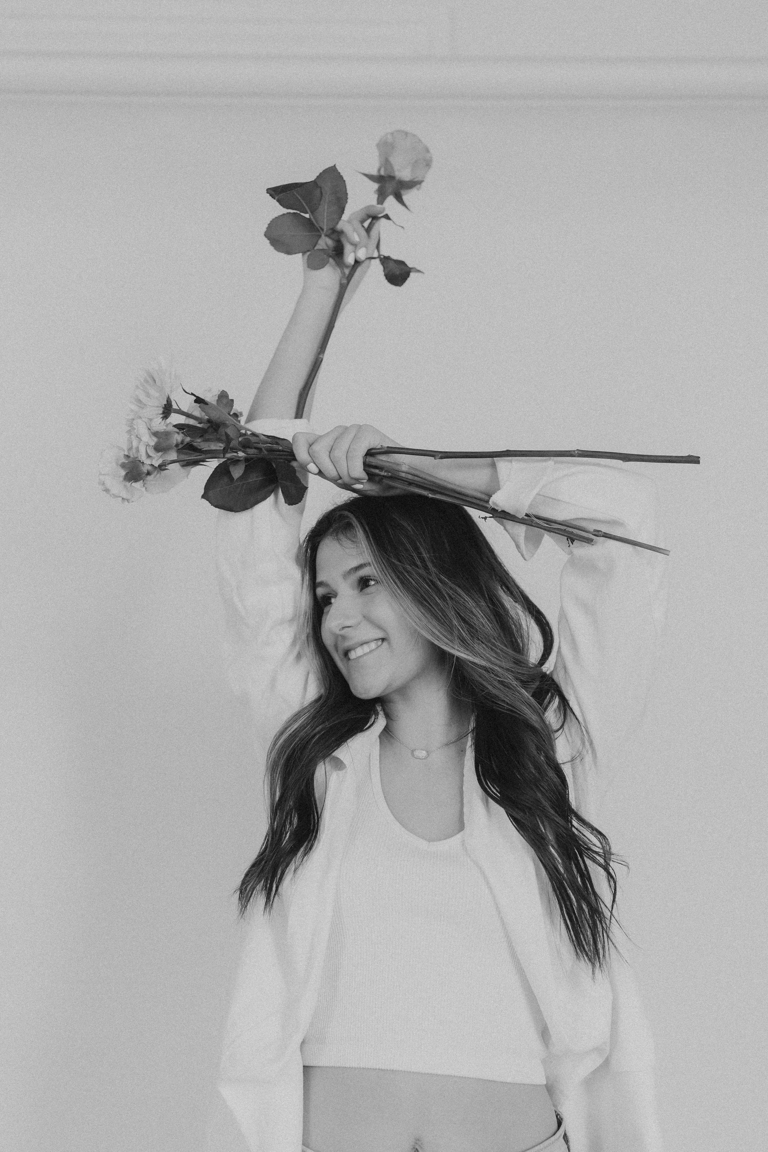  a woman holds long stems of flowers above her head for business branding photography 