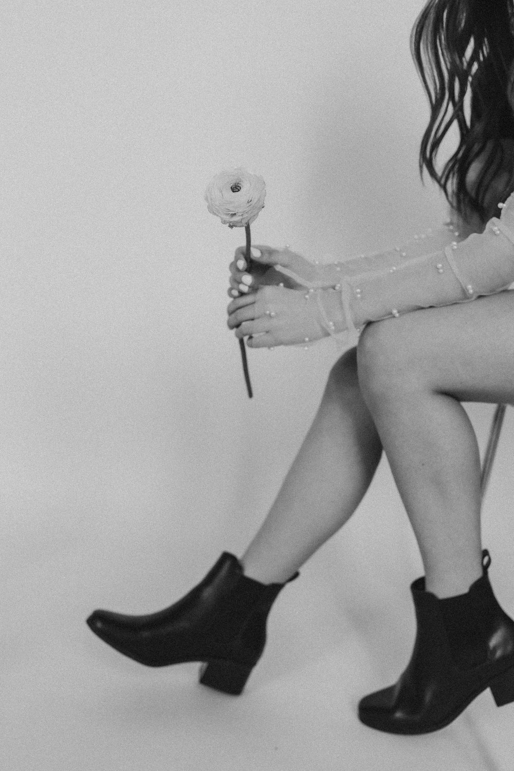  a woman sits and holds out a single flower 