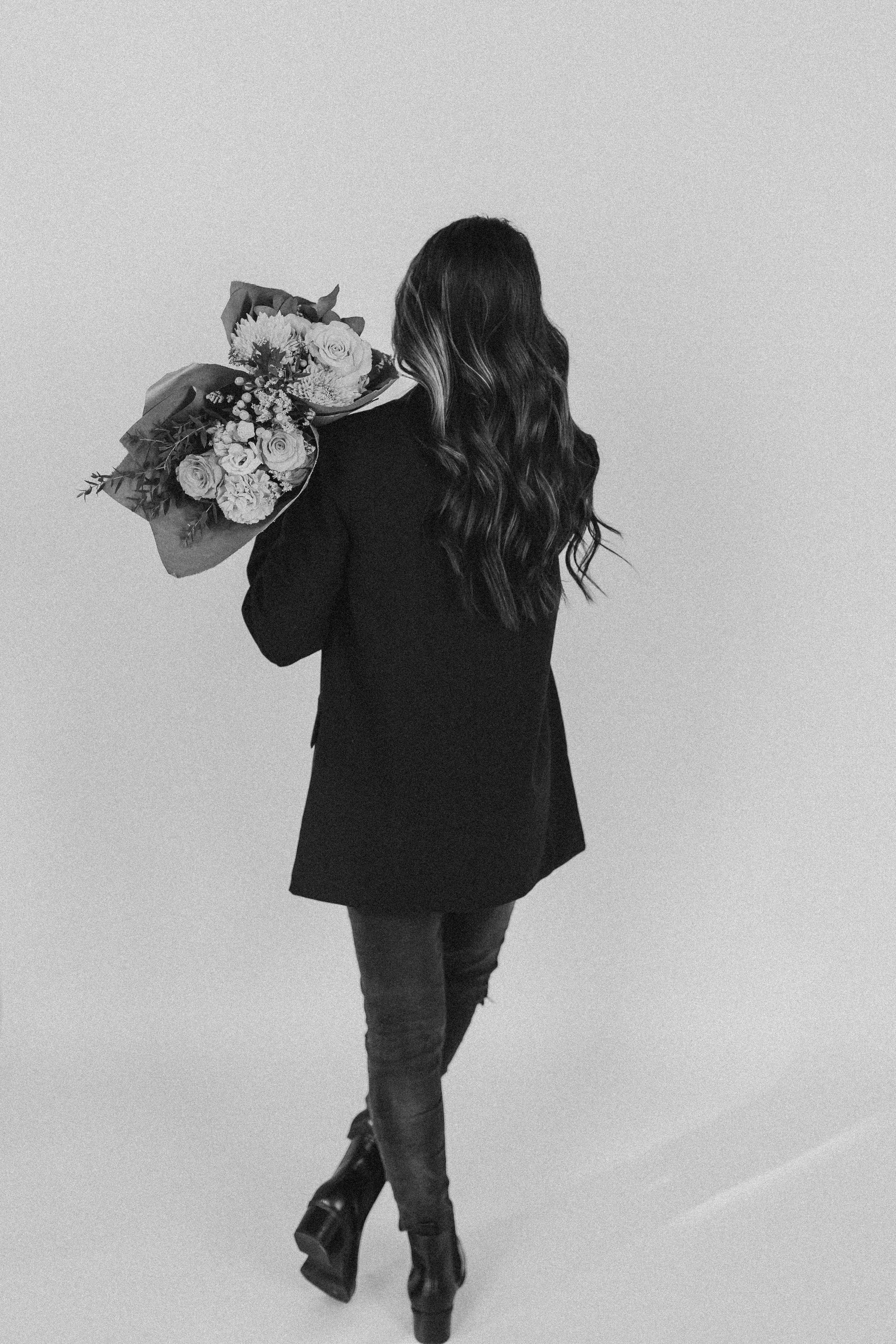  a woman stands while holding bouquets of flowers 