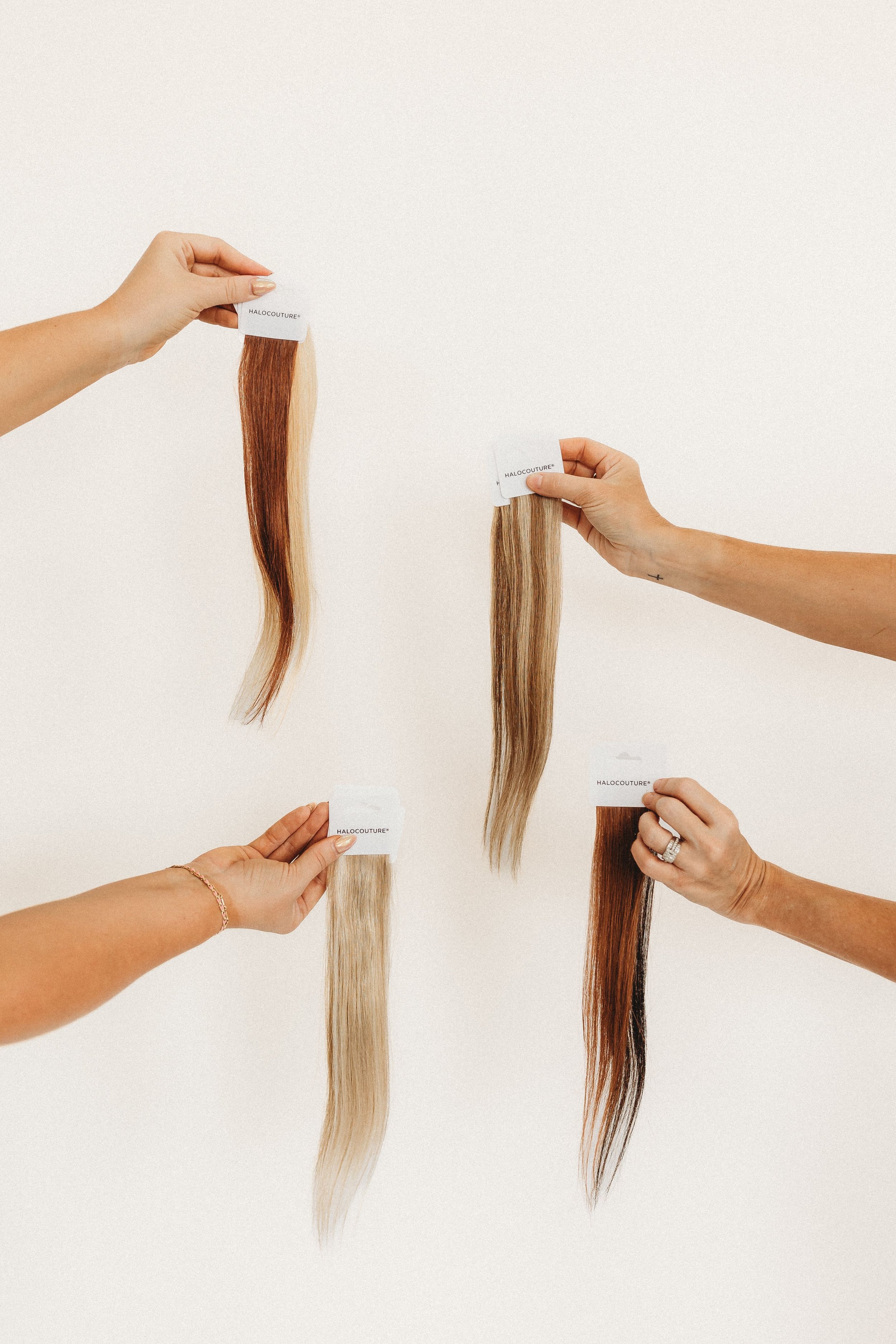  four hands hold up samples for hair extensions 