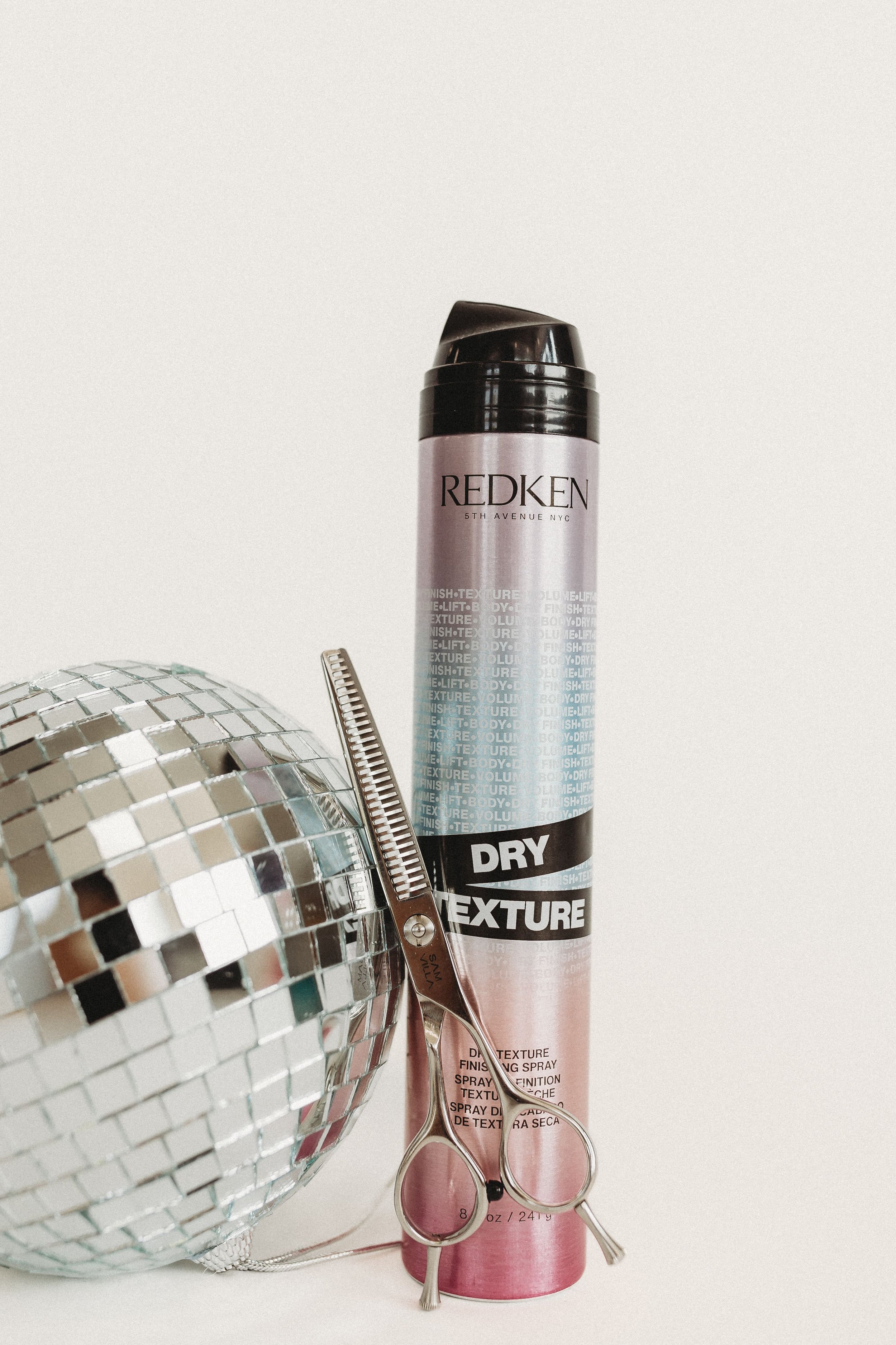  a pair of sheers leans on a disco bal next to a bottle of dry texture spray 