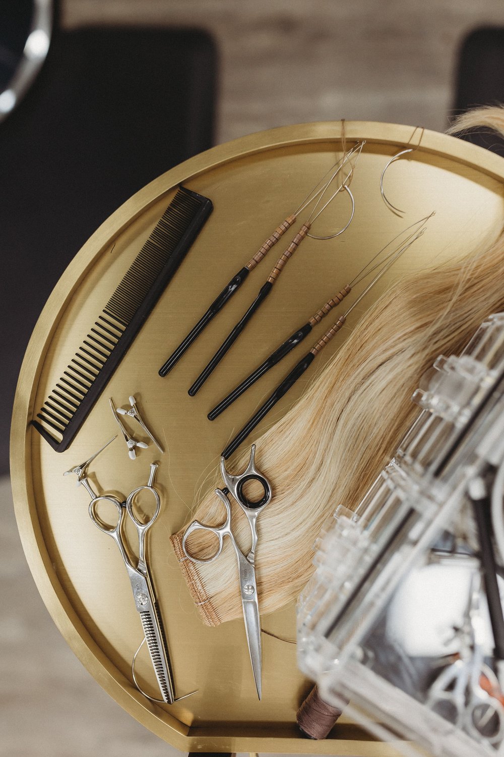  hair extension tools sit on a gold tray during a stylist photoshoot 