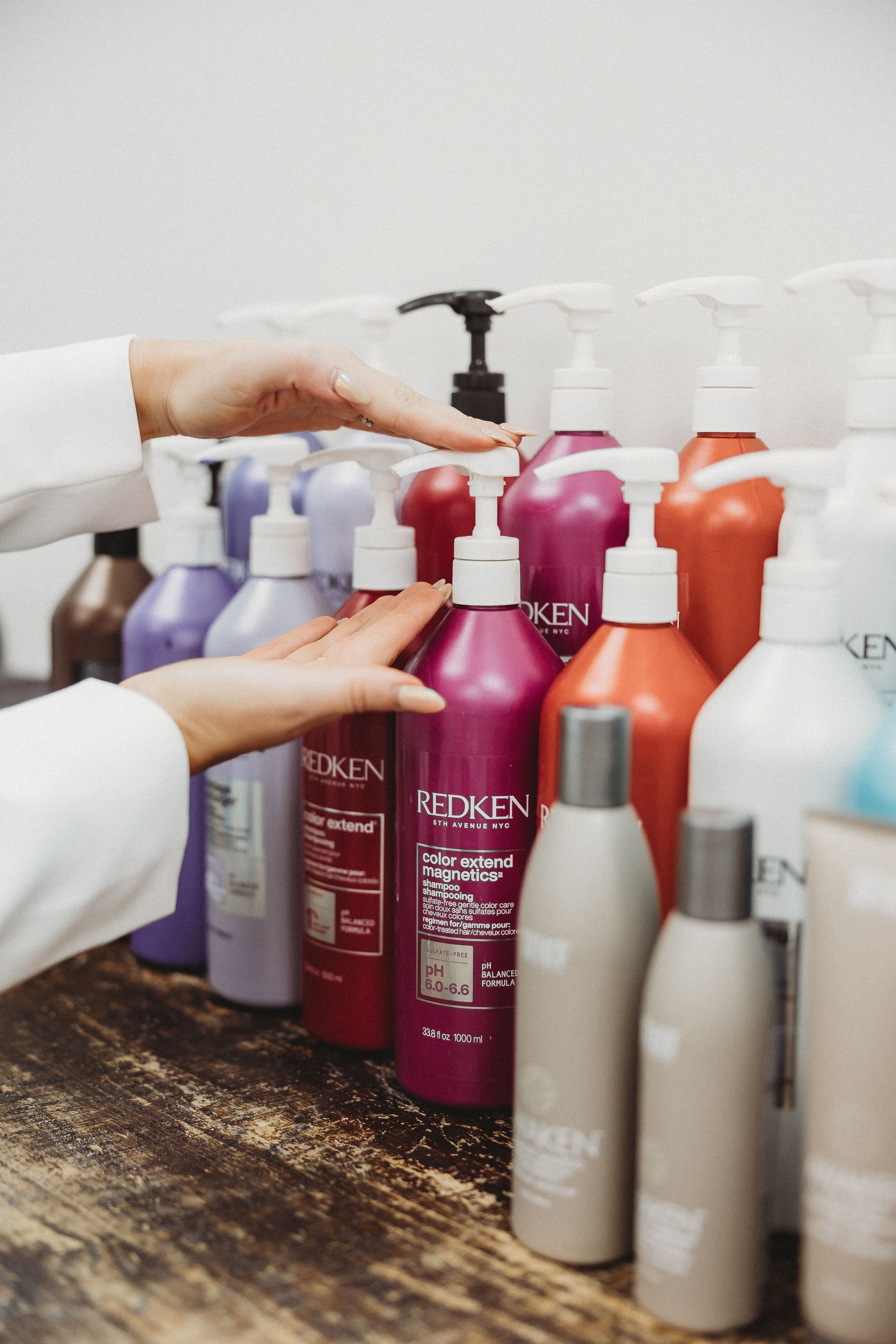 a pair of hands reach out for a pump from a conditioner bottle during a stylist photoshoot 