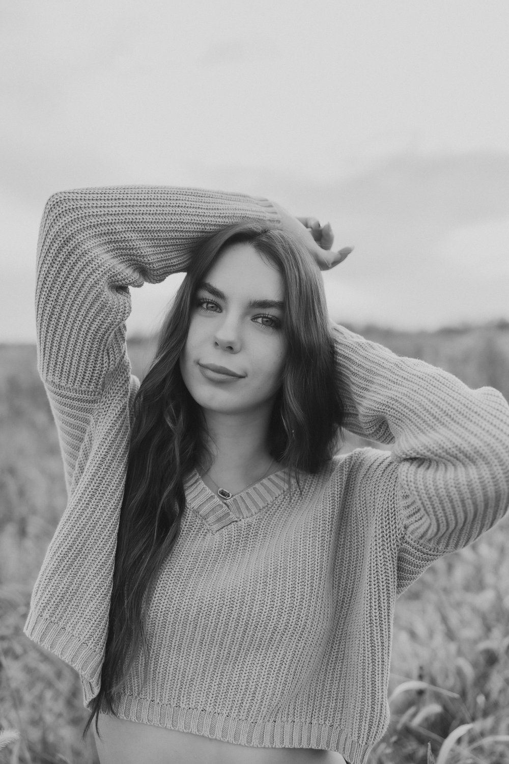  a black and white portrait of a senior girl that smiles softly for her senior photos 