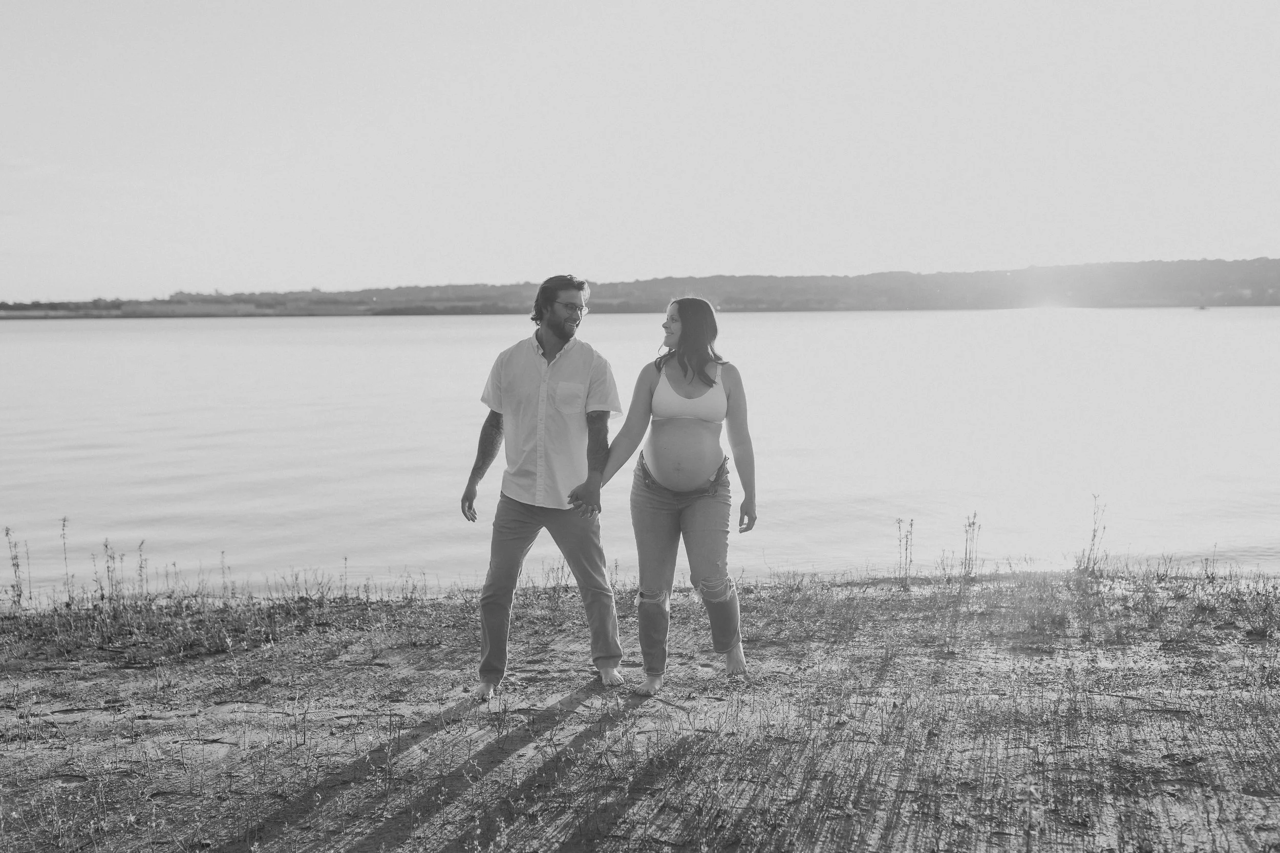  a man looks over at his wife during their maternity photos on the beach 