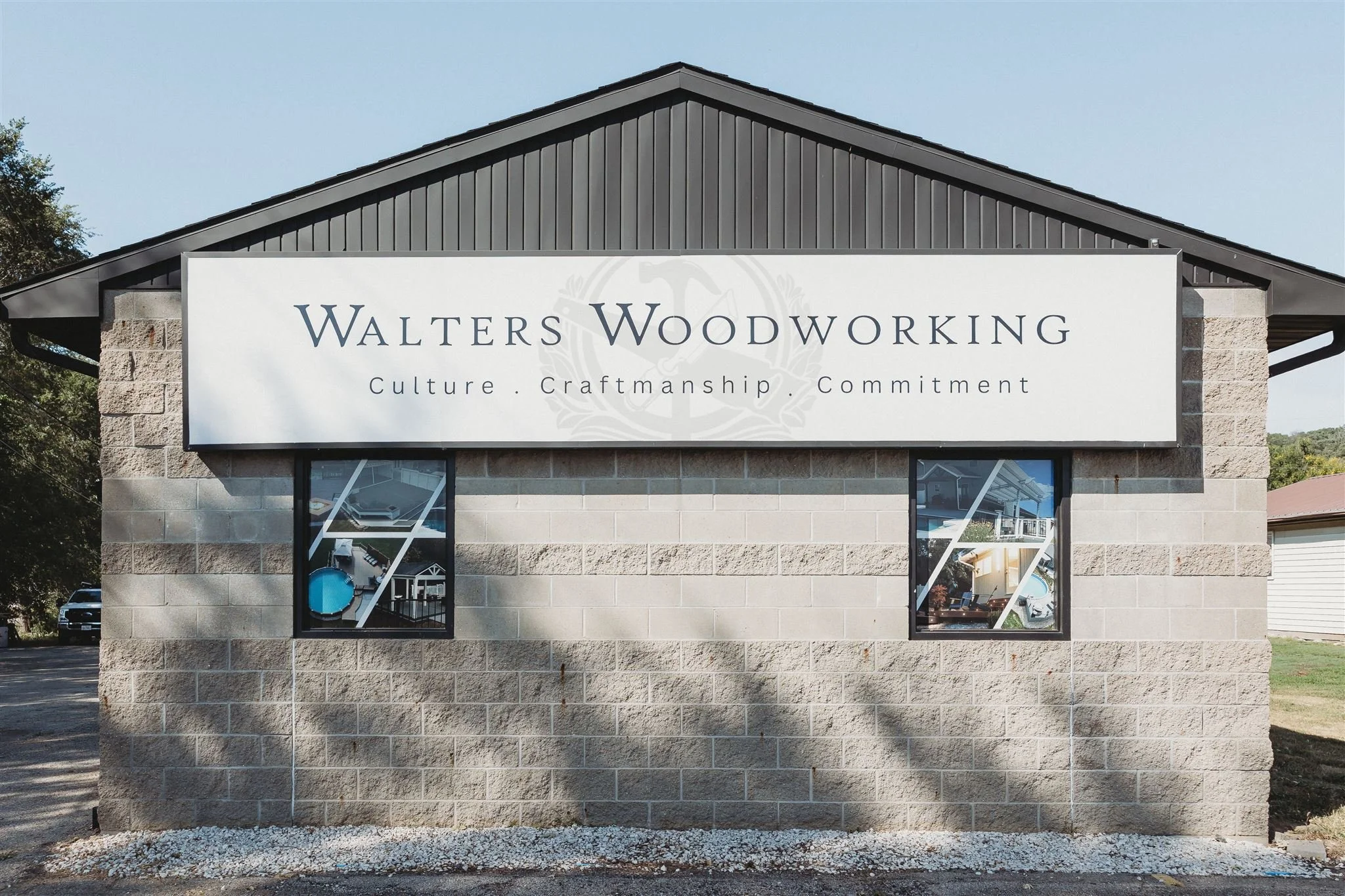 Exterior storefront of Walters Woodworking, a custom woodworking and craftsmanship business, featuring a bold branded sign with their tagline "Culture. Craftmanship. Commitment" on a stone building facade.
