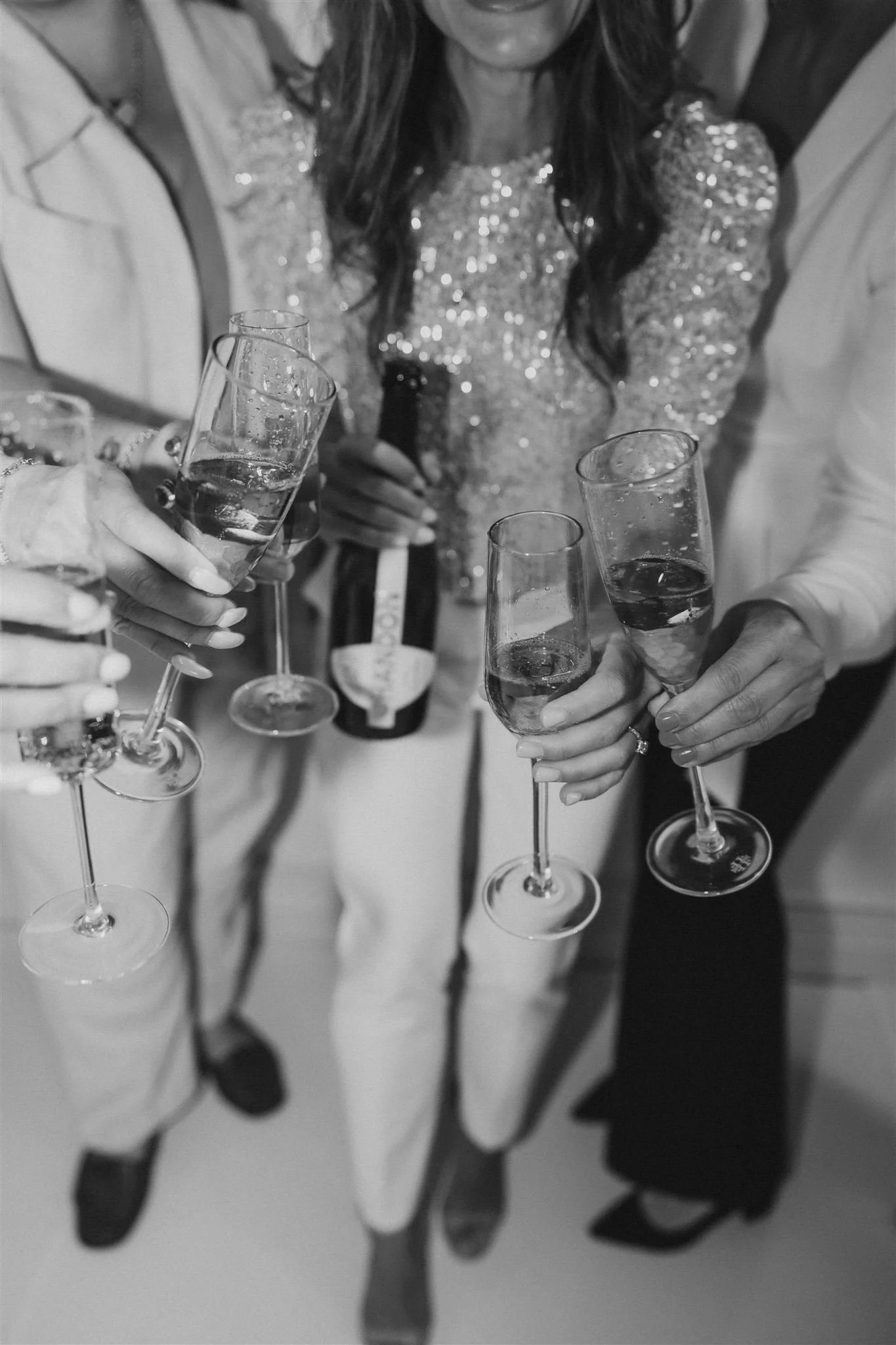 People holding glasses of champagne at a celebration, with one person pouring a drink from a bottle.